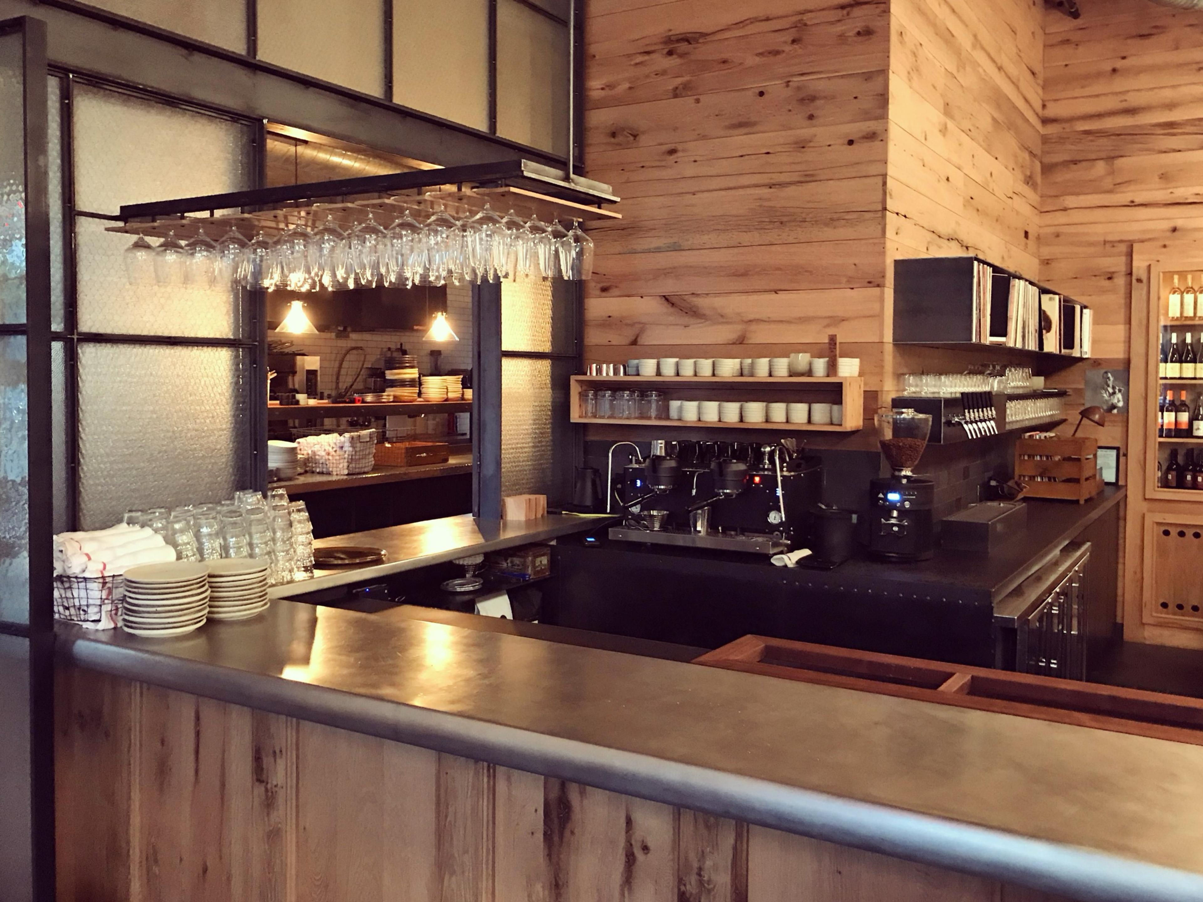 A wood-panelled bar and open kitchen, glasses hanging above the counter