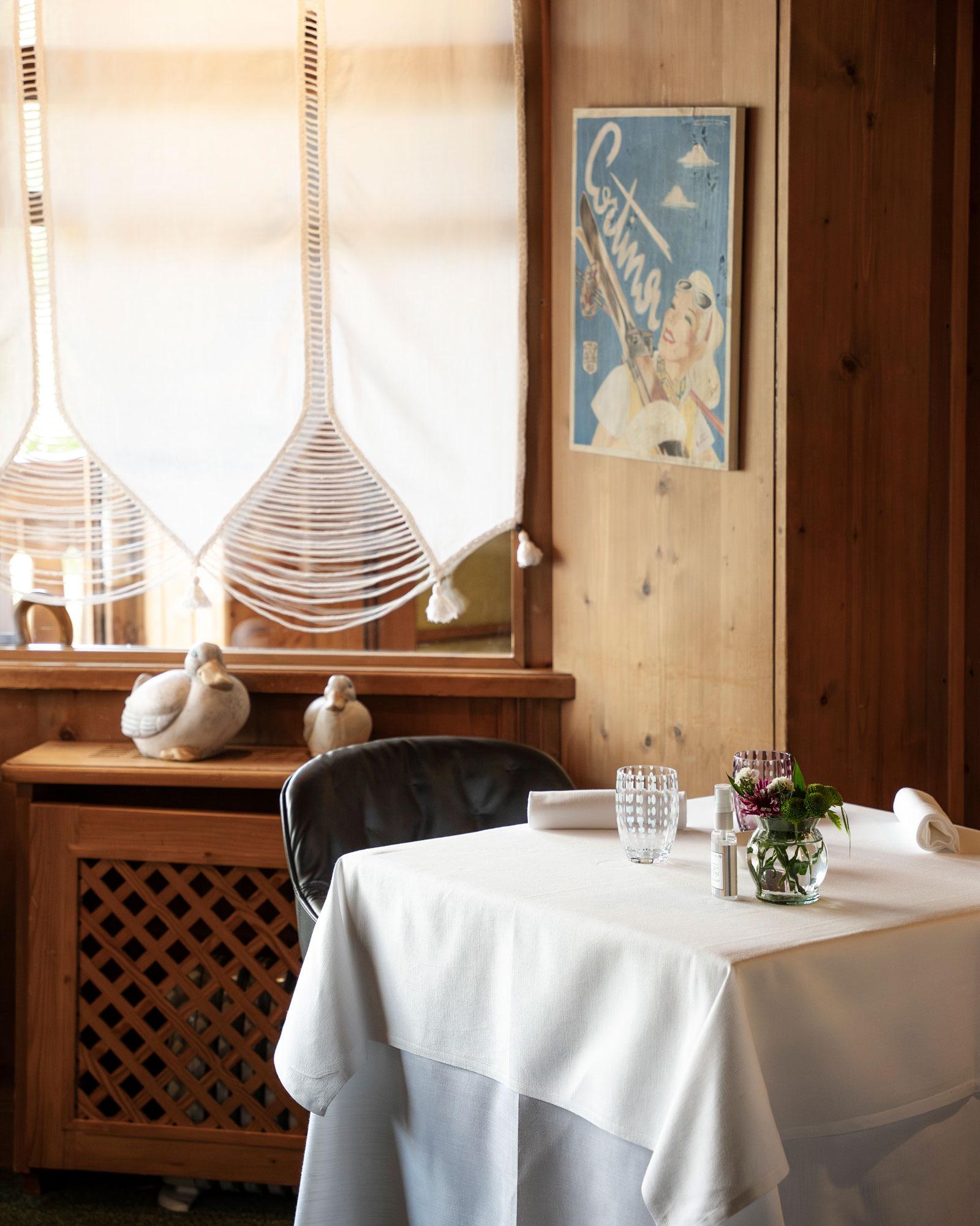 A white-clothed table by a window in a pine-panelled dining room