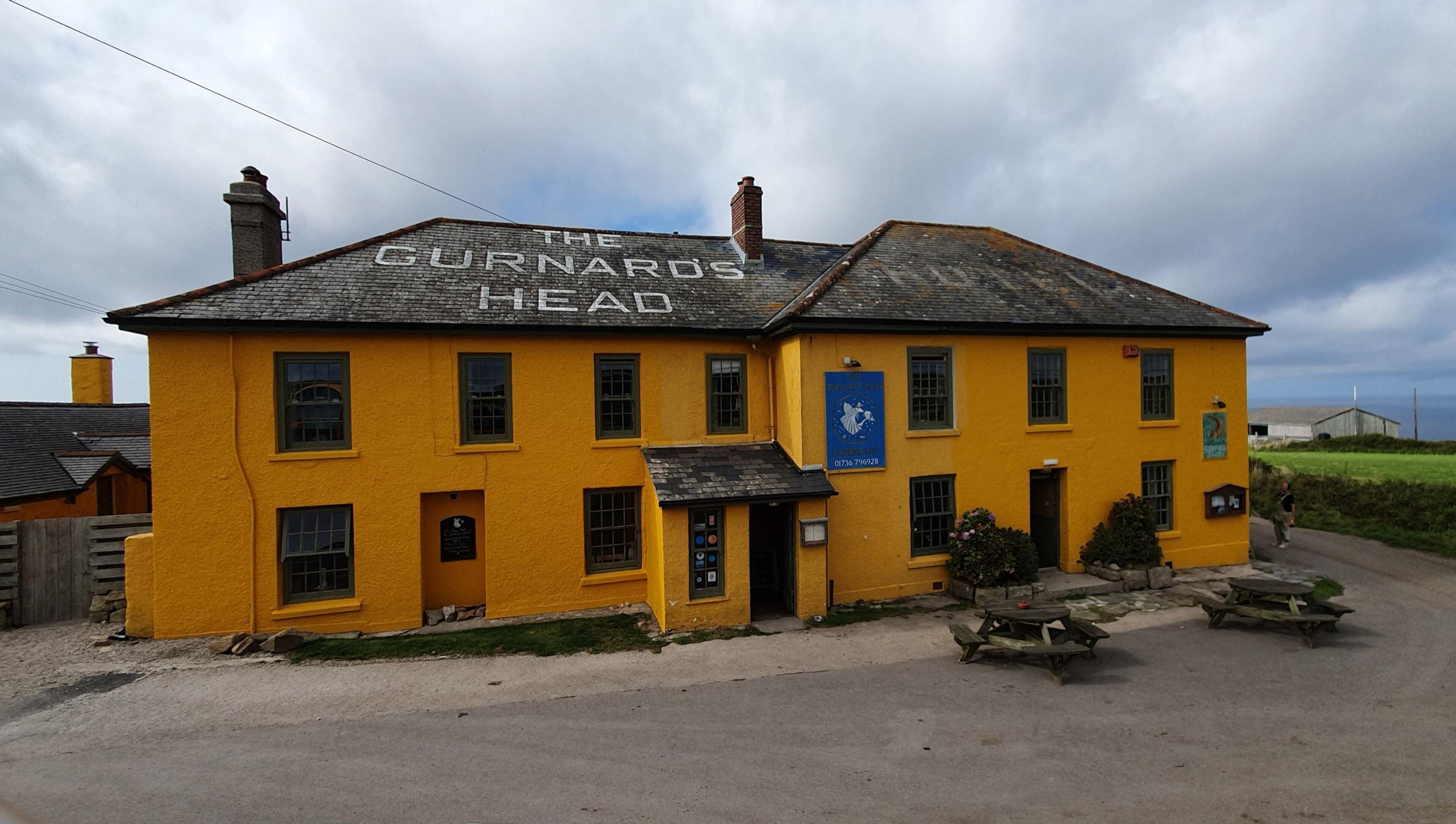 The Gurnard's Head, a yellow-painted inn with its name on the slate roof, beside the road at Treen.