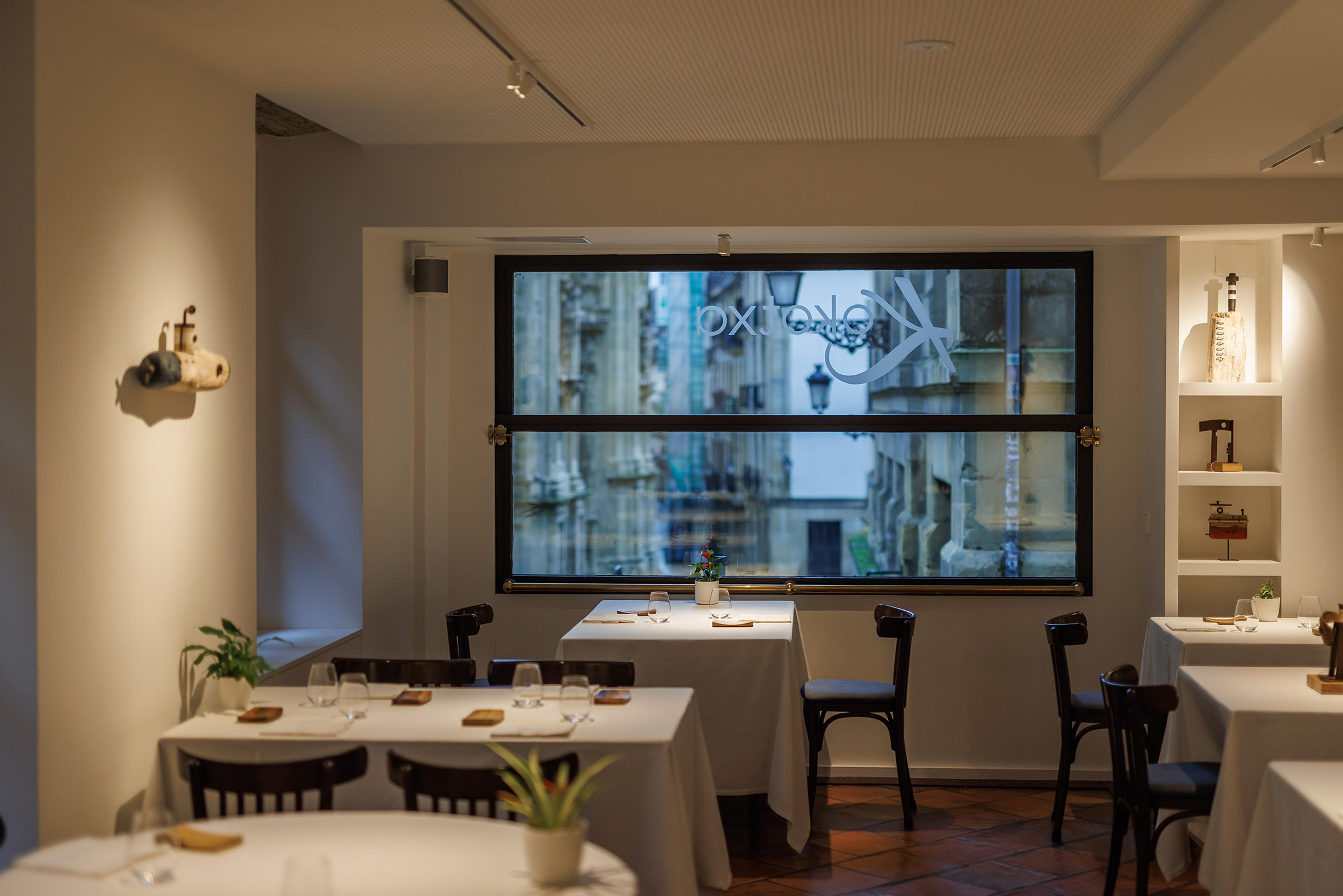 Kokotxa's dining room in the old town, laid tables and a window onto the kitchen