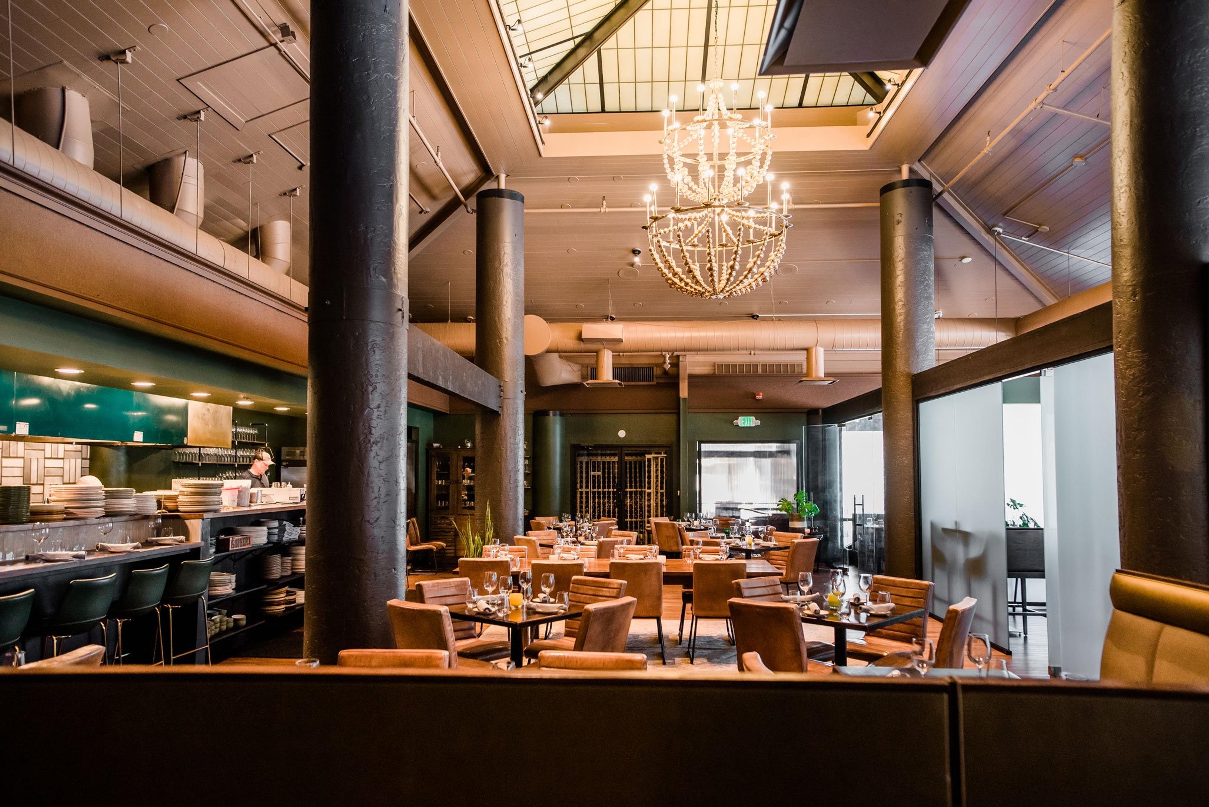 A high-ceilinged dining room with wooden tables and chandeliers