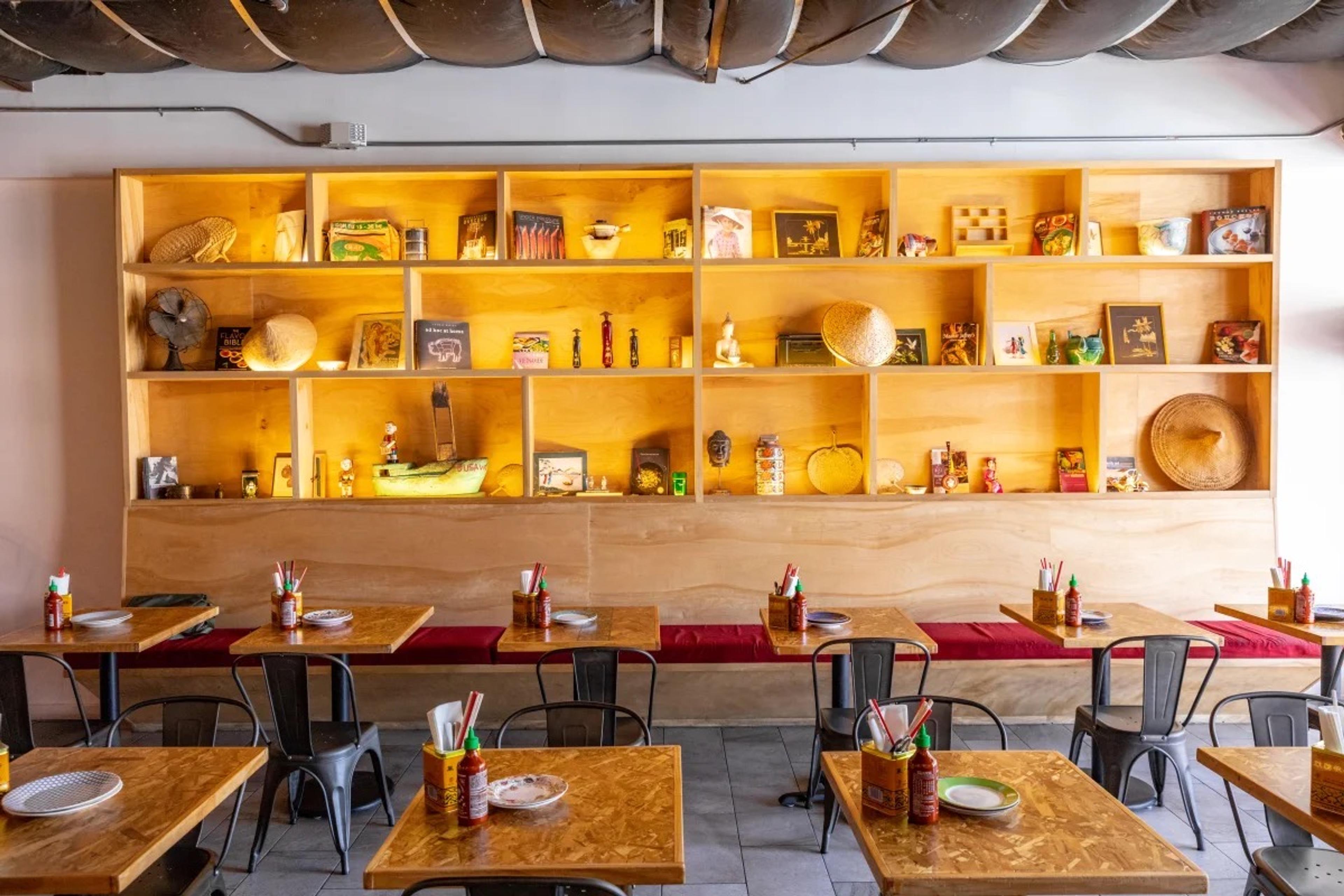 A small dining room with shelves of jars and plants behind its tables