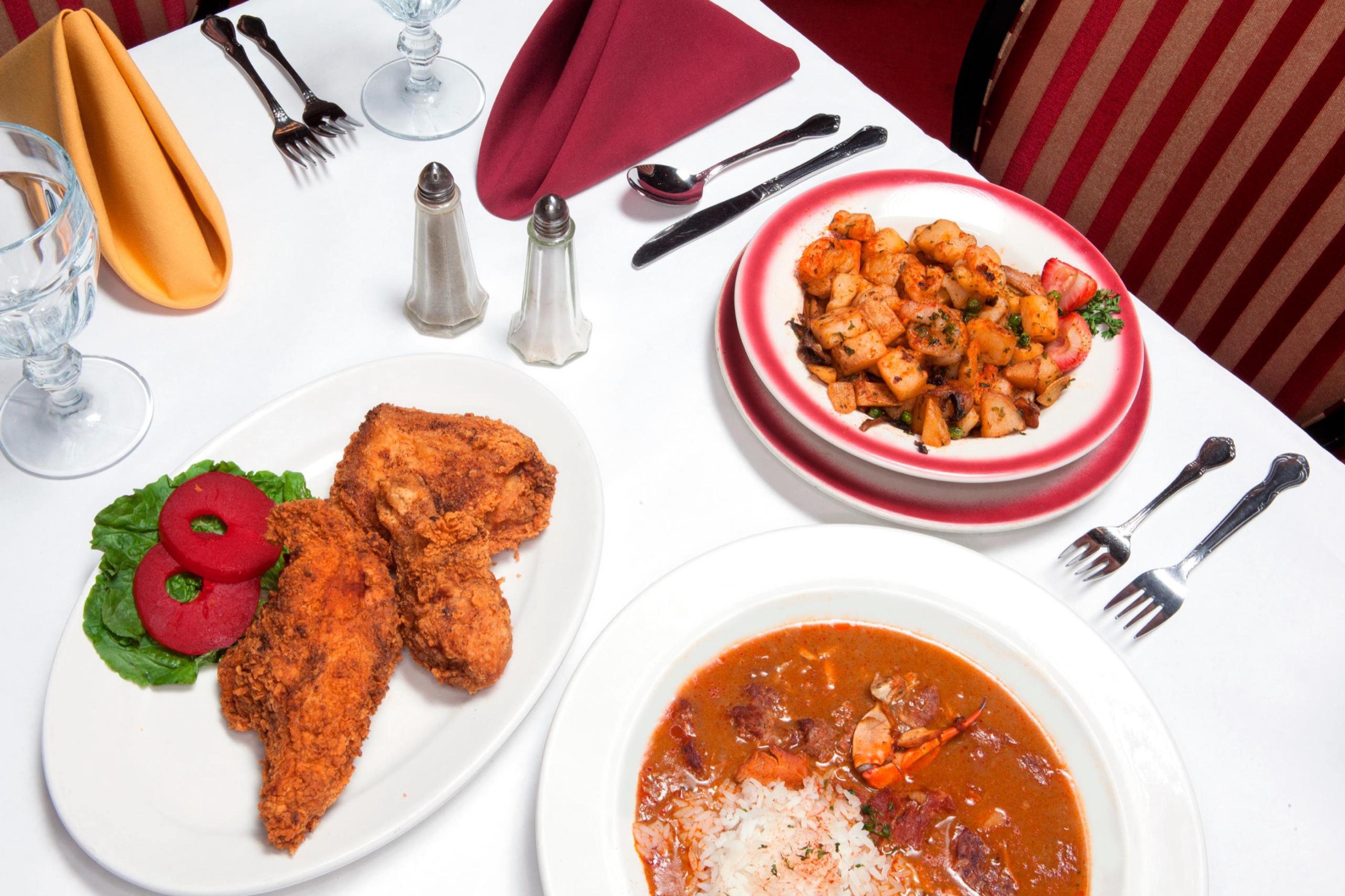 Fried chicken and a bowl of gumbo on a white tablecloth
