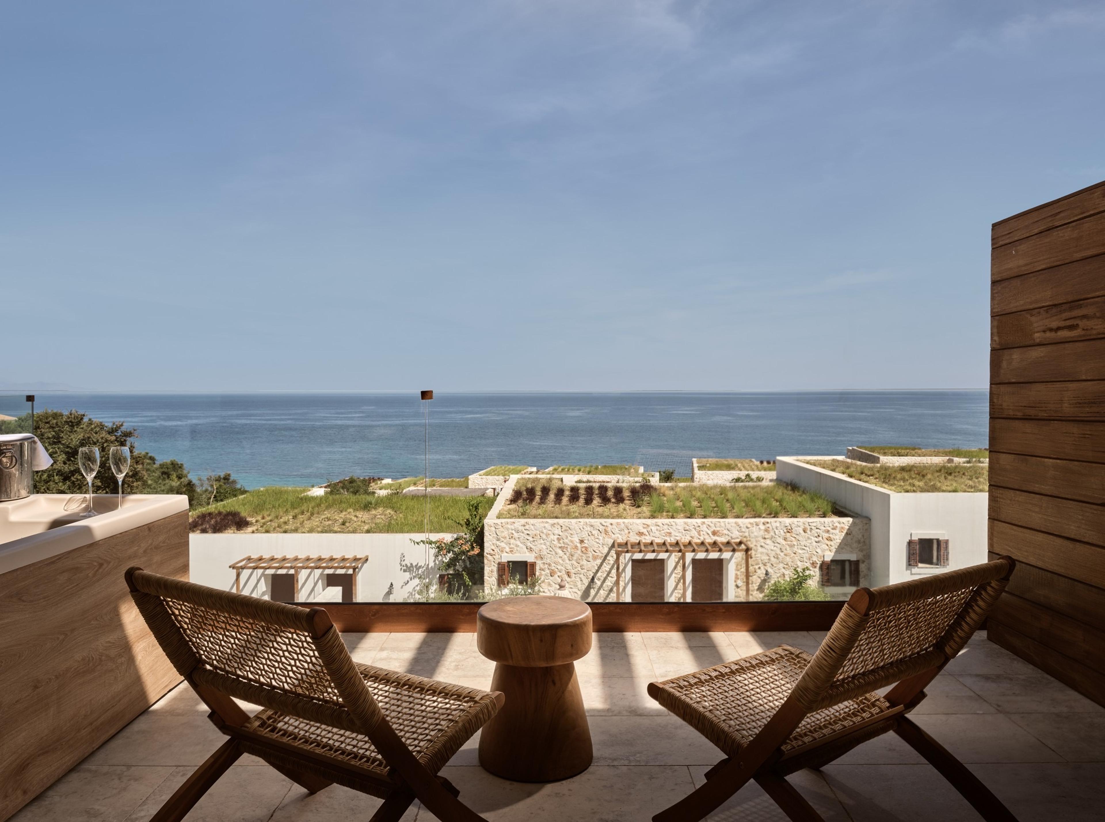 A private terrace with a stone-edged bathtub, two glasses on its rim, and twin loungers facing the open sea.