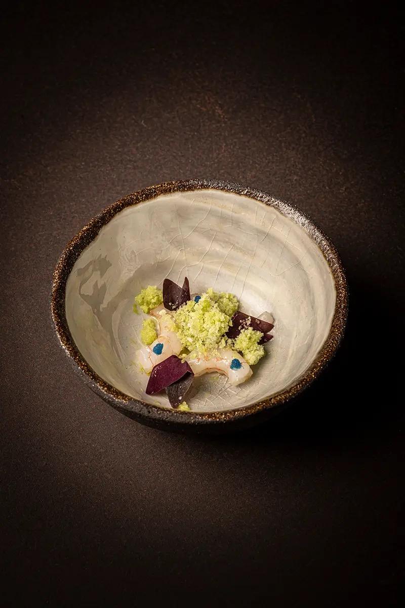 A small plated dish in a pale ceramic bowl on a dark wooden table