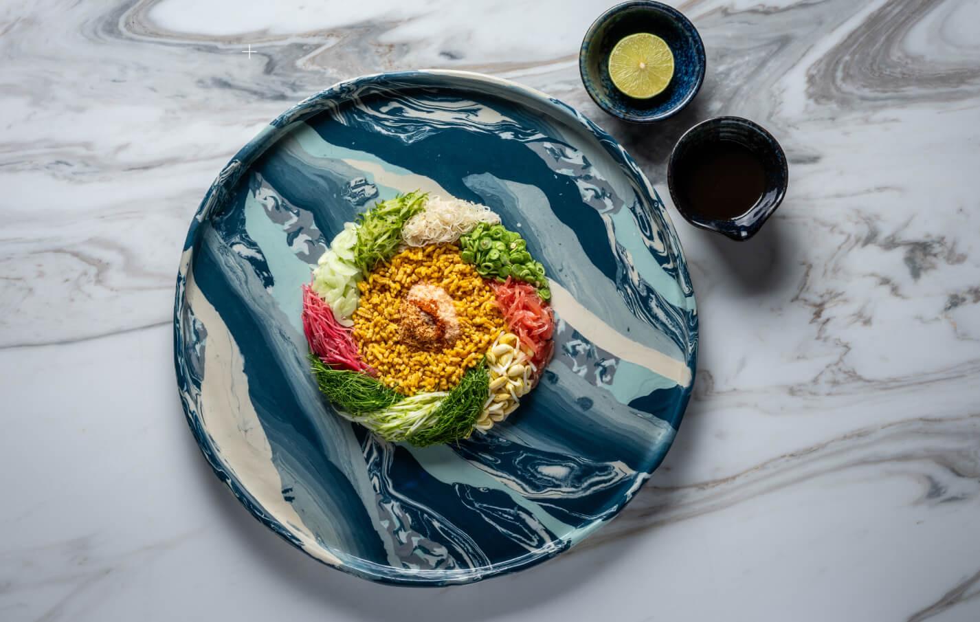 A plate of southern Thai food in bright colours on a blue ceramic dish