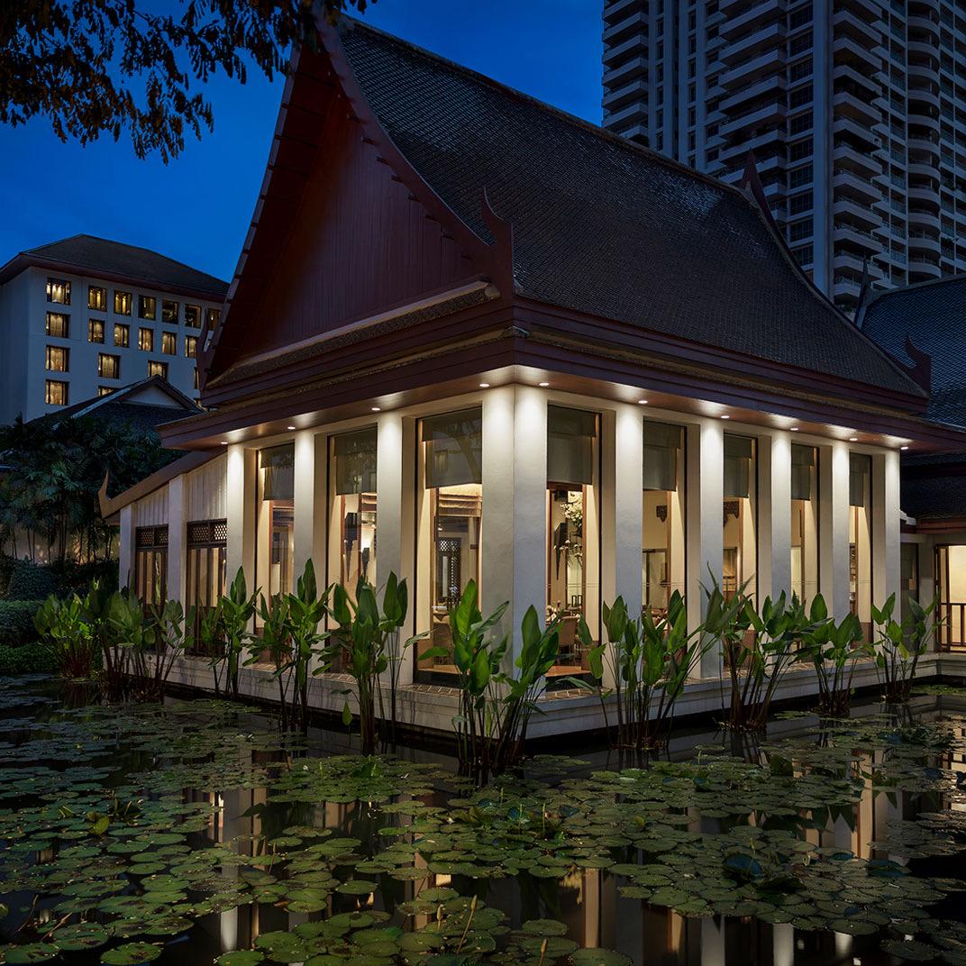 A lantern-lit pavilion at dusk among trees
