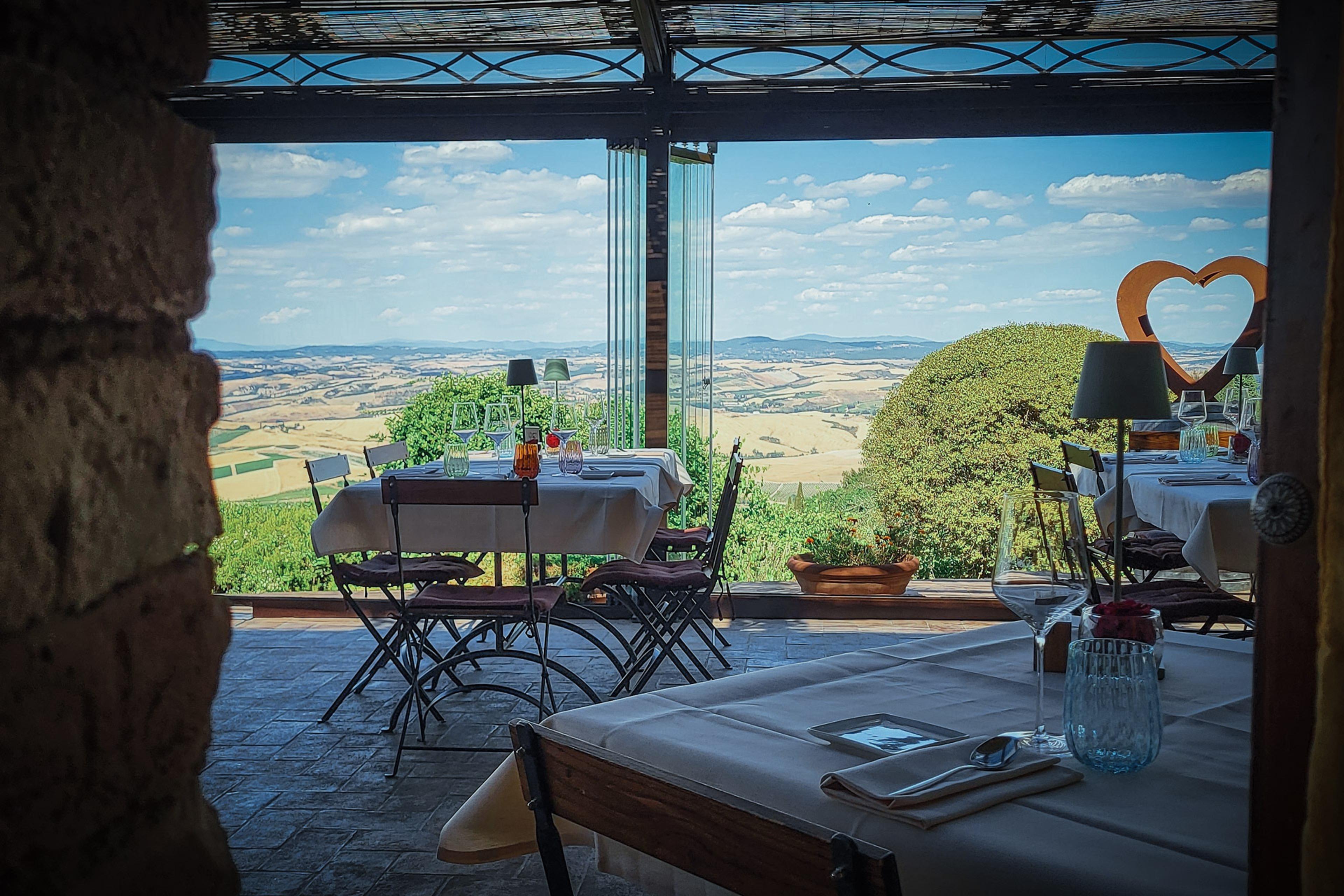 A shaded terrace of tables looking out over the open Tuscan countryside.