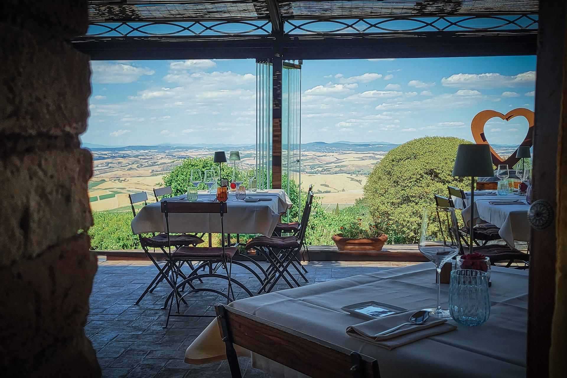 A shaded terrace of tables looking out over the open Tuscan countryside.