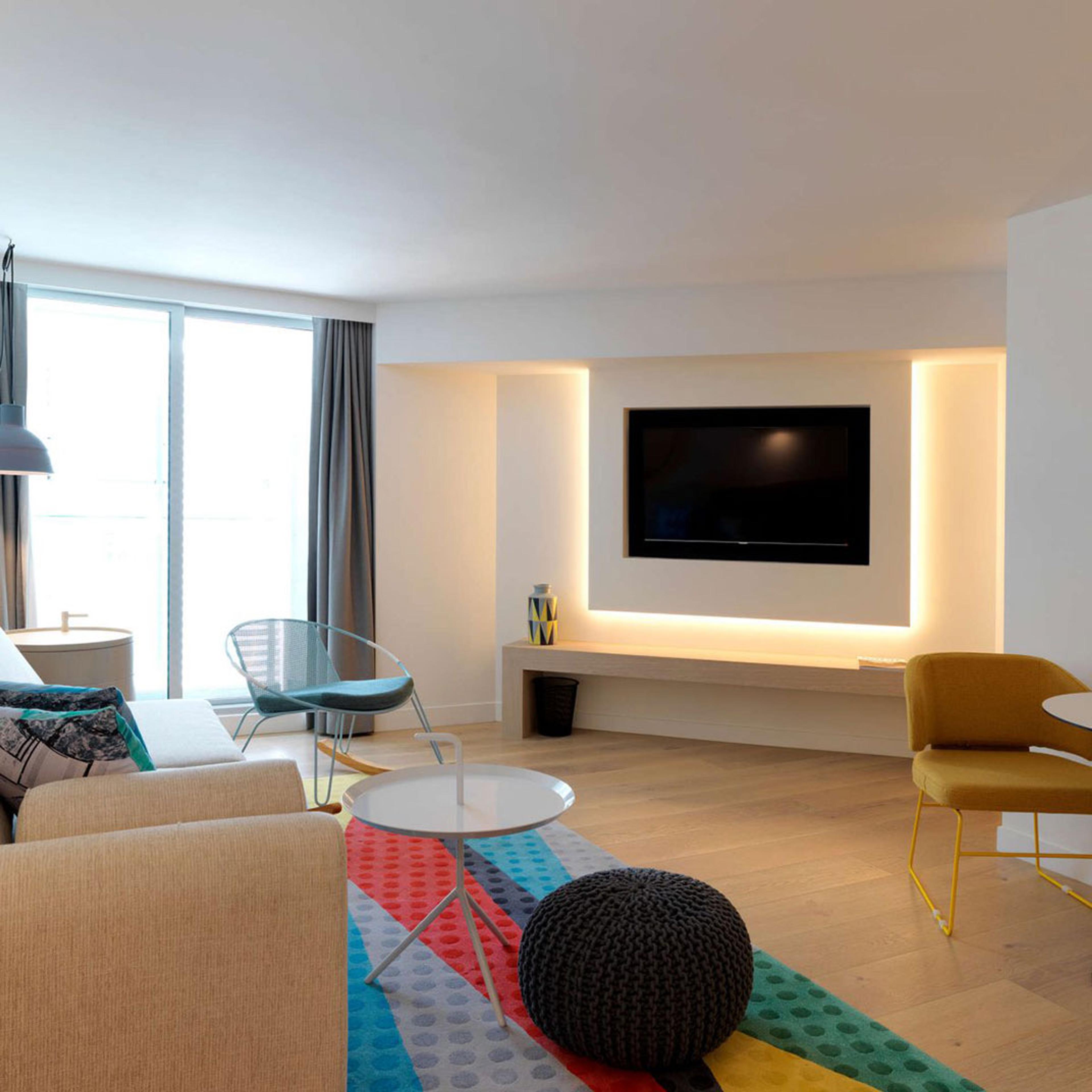 A white living room with a long sofa and a wall-mounted television