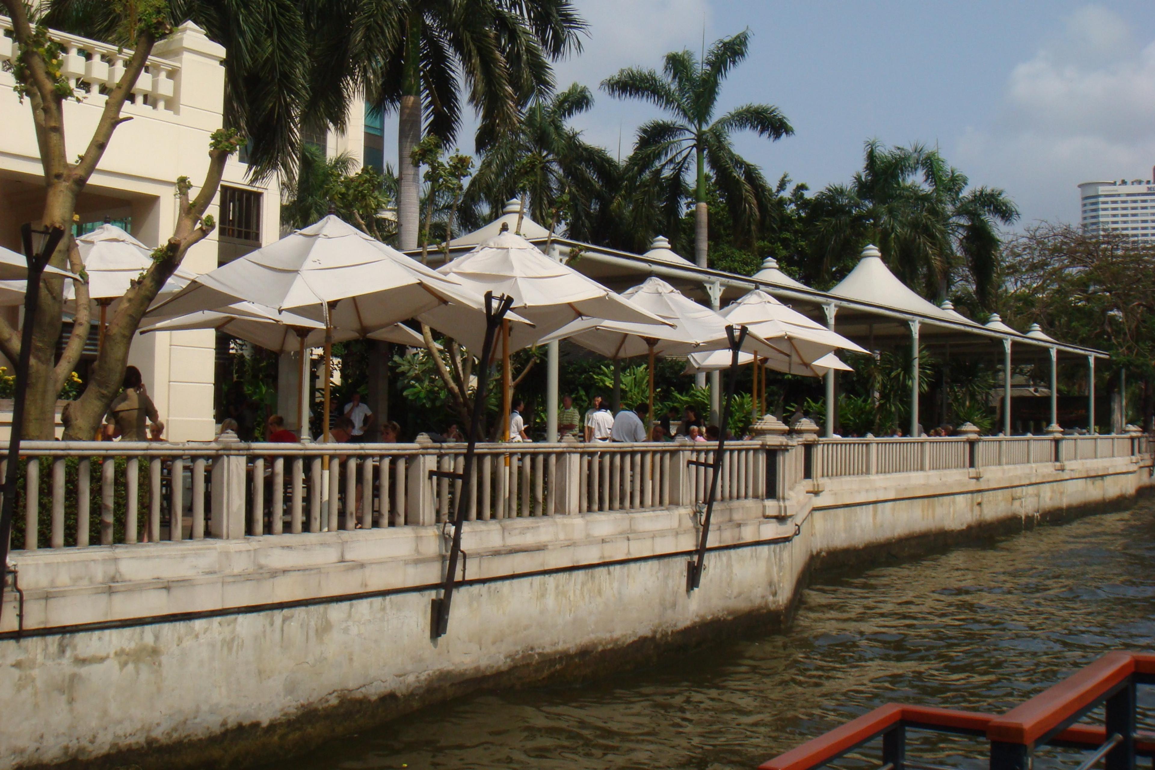 White umbrellas along the hotel's riverside terrace above the water