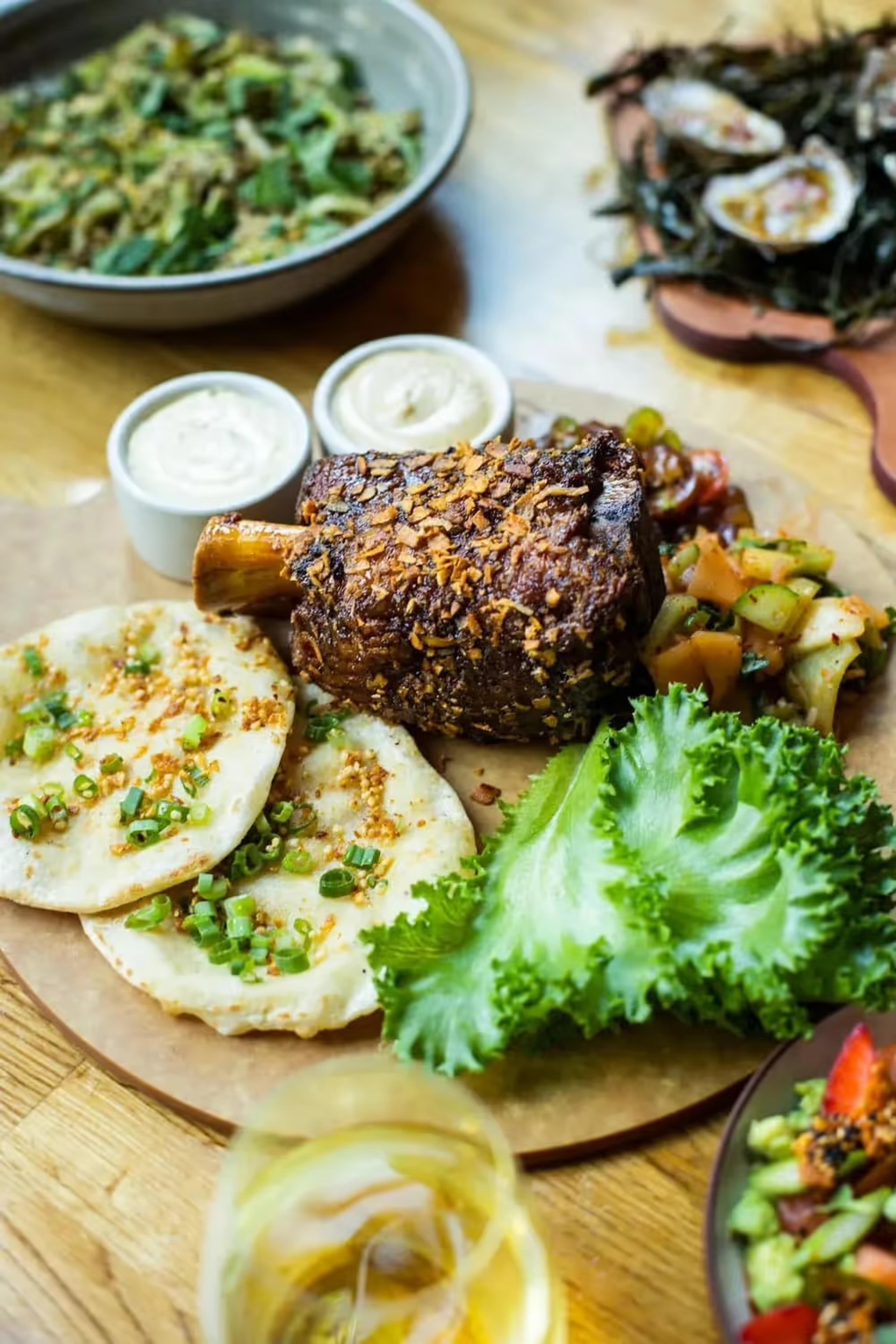 A spread of dishes at Girl & the Goat, with flatbreads and a bowl of greens