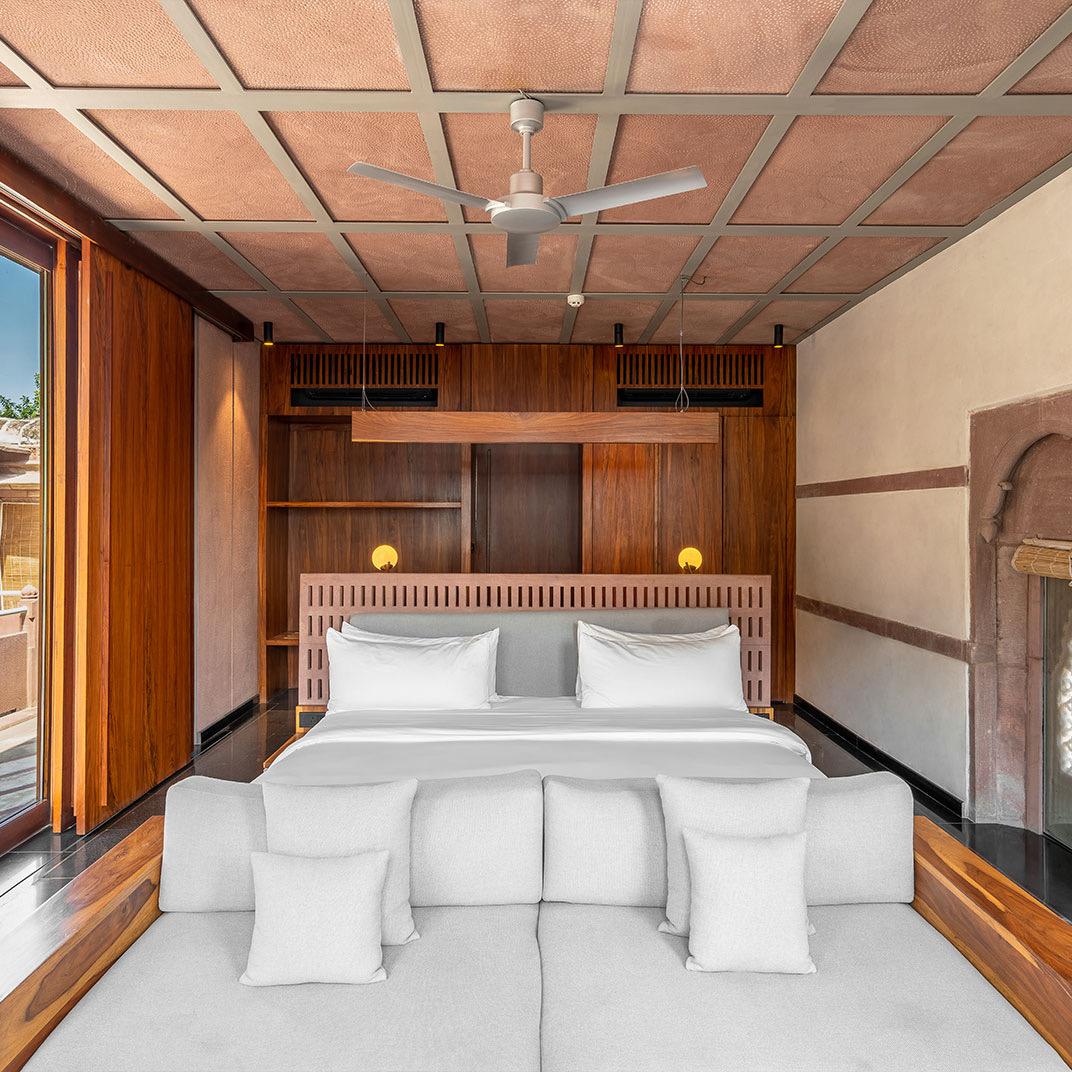 A bedroom in dark wood and white linen