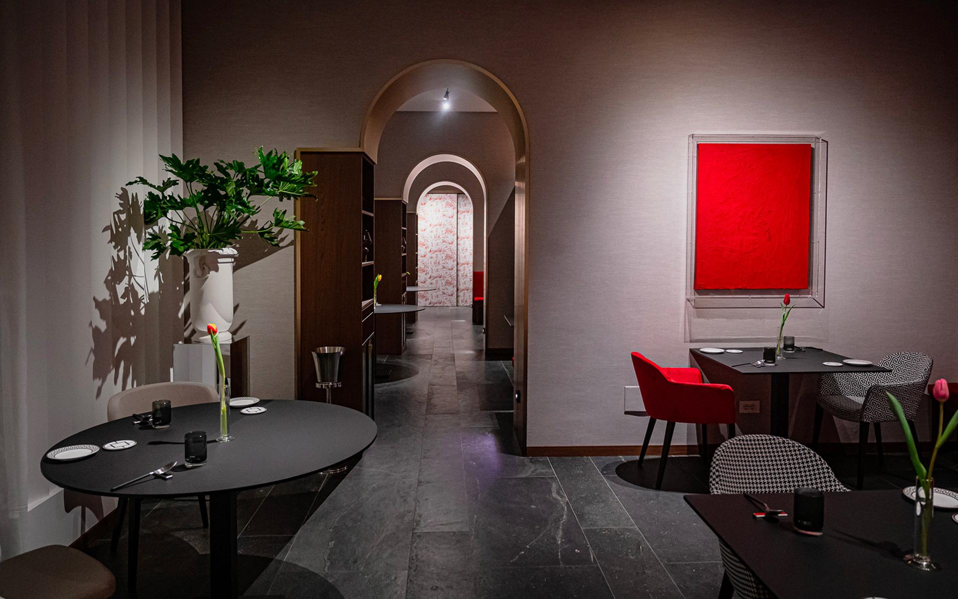 Coria's dining room in Catania, dark tables and grey chairs under a single red canvas on the wall