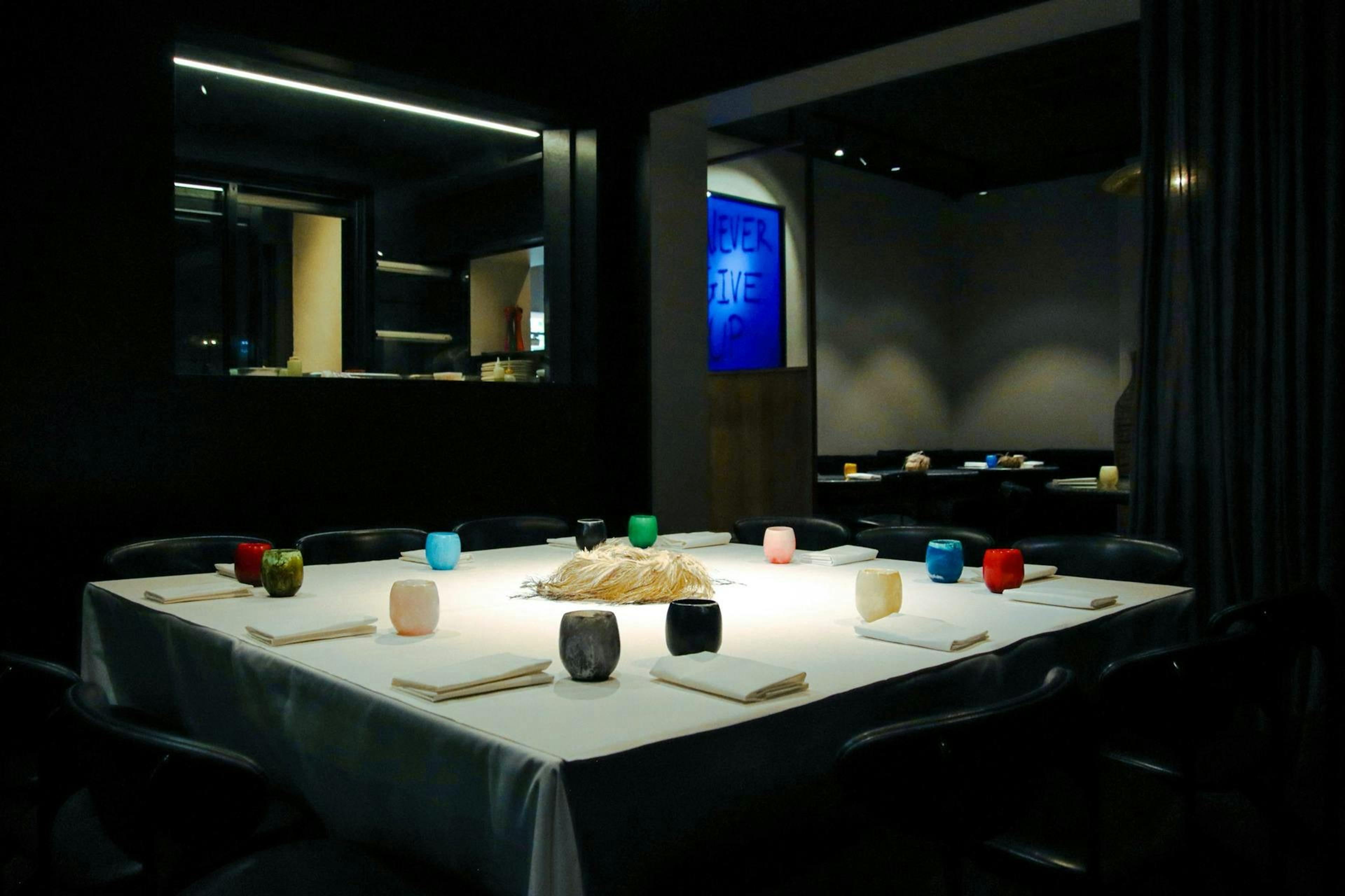A dark dining room with a white-clothed table lit from above