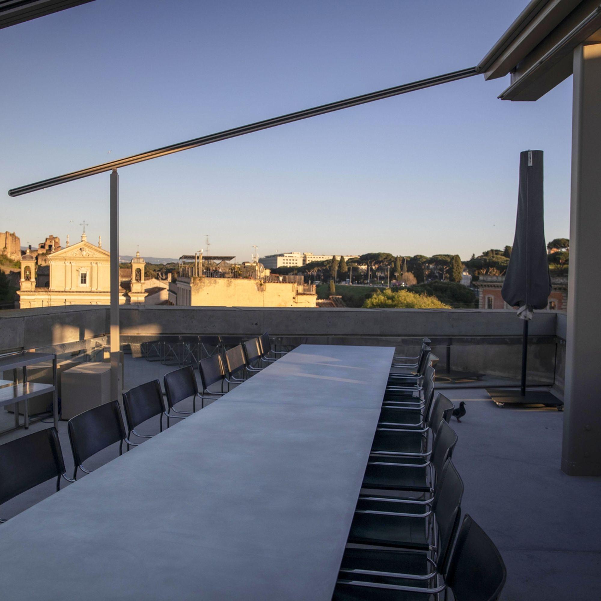 A long table on a terrace above the rooftops of Rome in the evening light