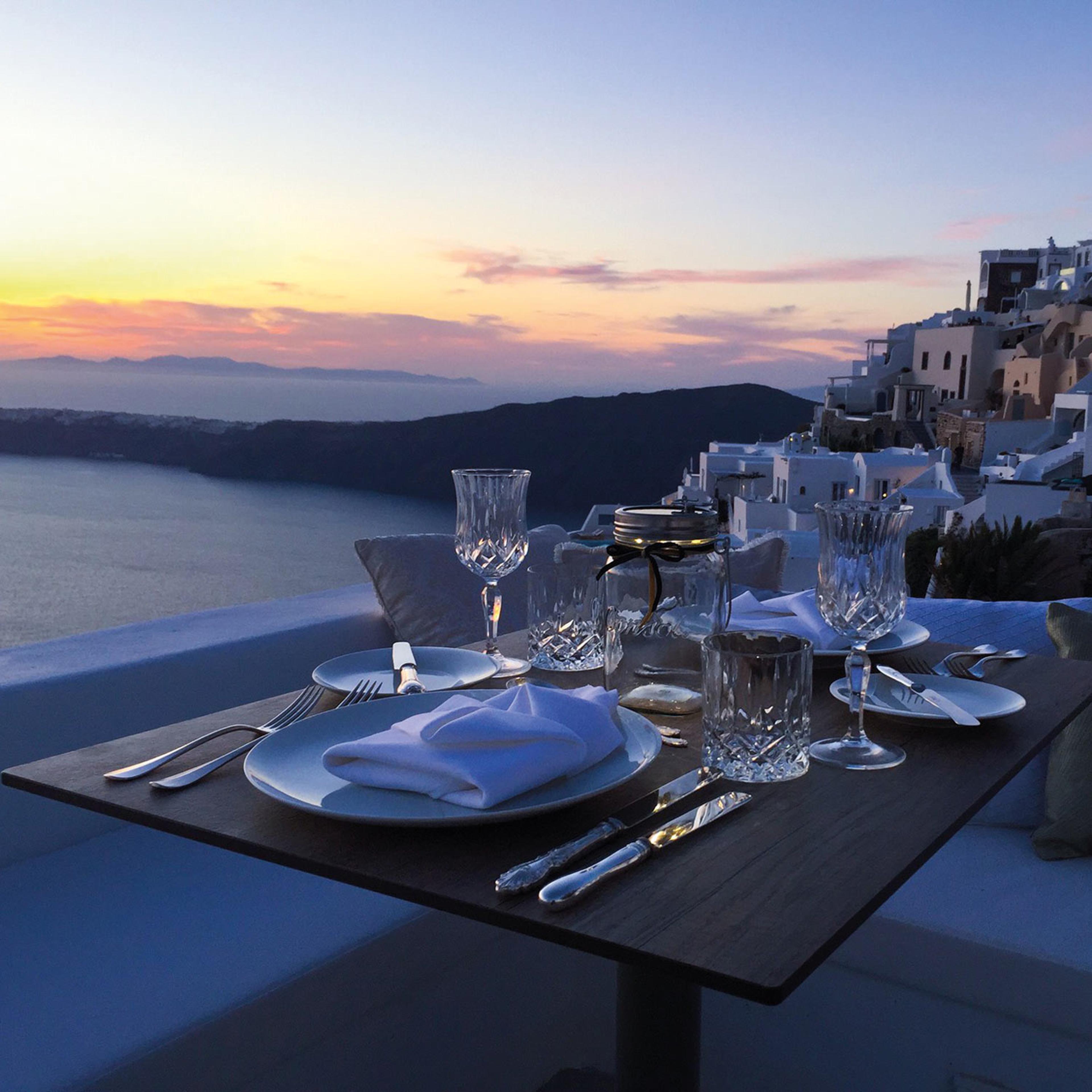 A table laid on a terrace above the caldera at dusk