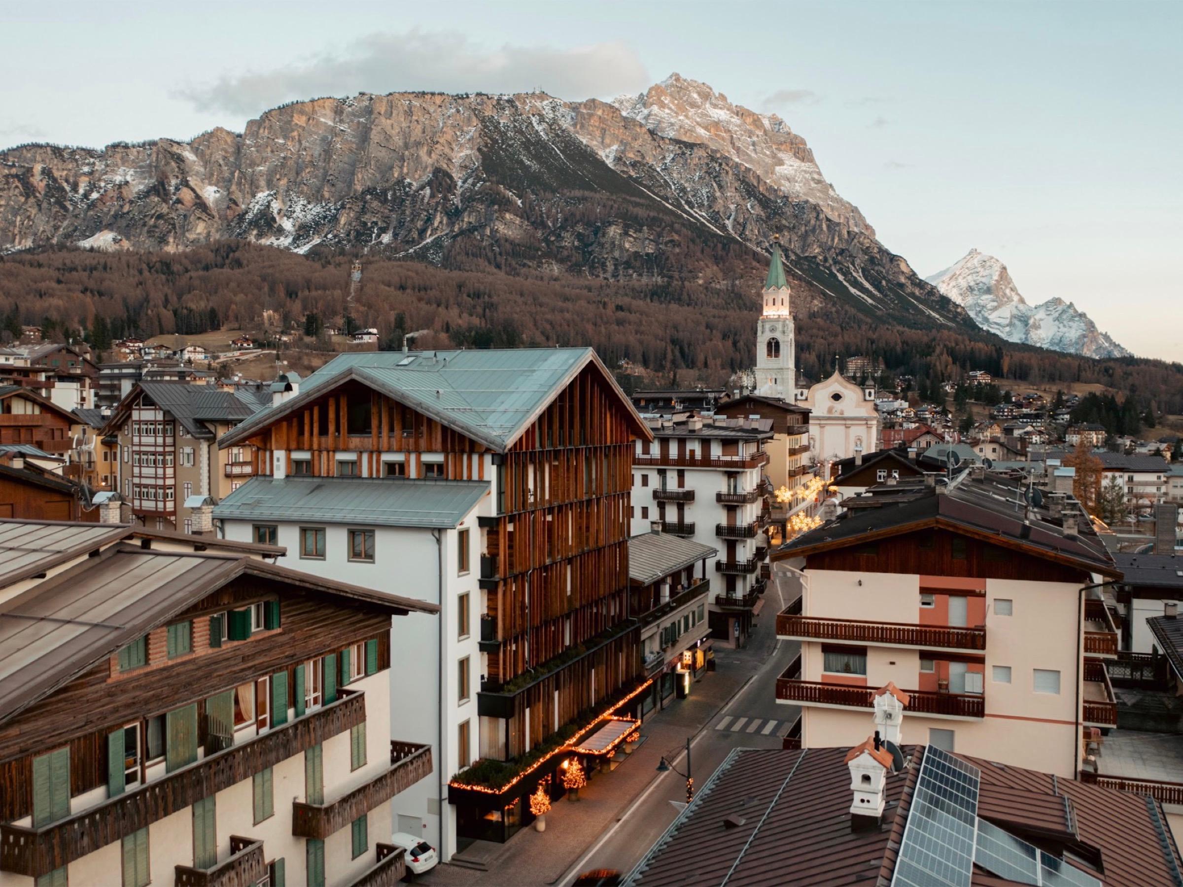 Cortina d'Ampezzo at dusk, its church tower above wood-clad roofs and the snow-streaked peaks behind