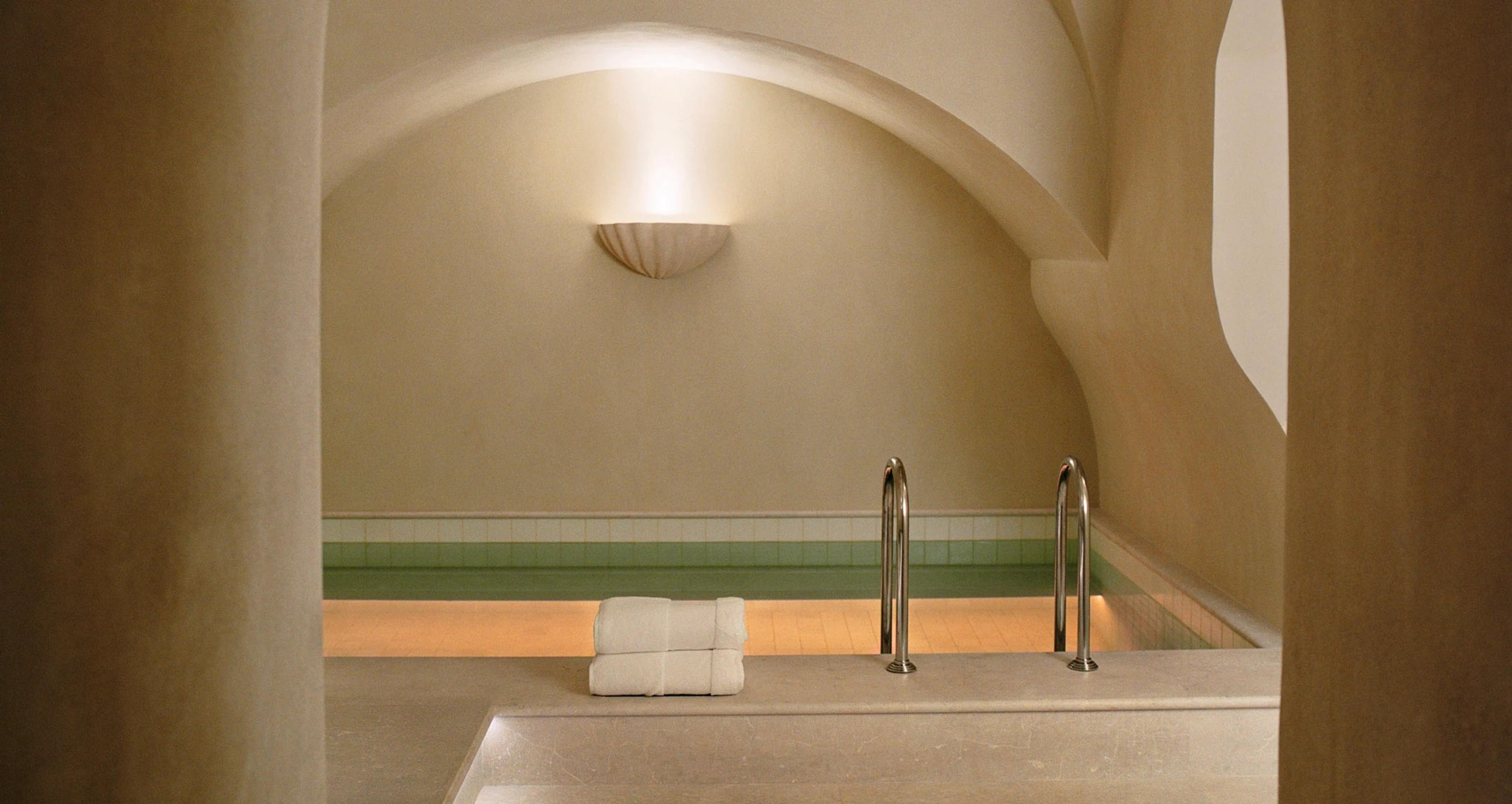 A small indoor pool under a vaulted cream ceiling, lit along its edge.