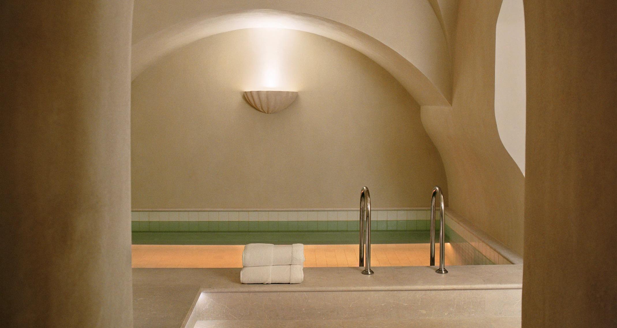 A small indoor pool under a vaulted cream ceiling, lit along its edge.