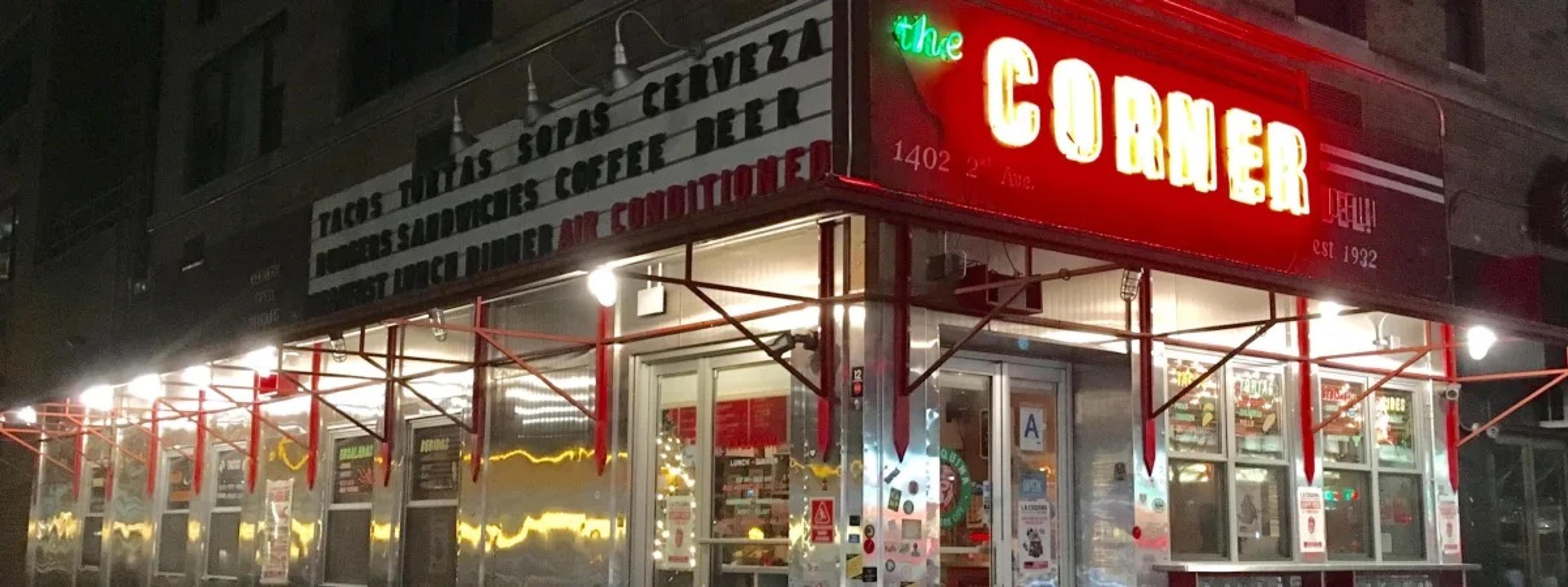 The red neon corner sign and lit windows of a small diner-style taqueria at night