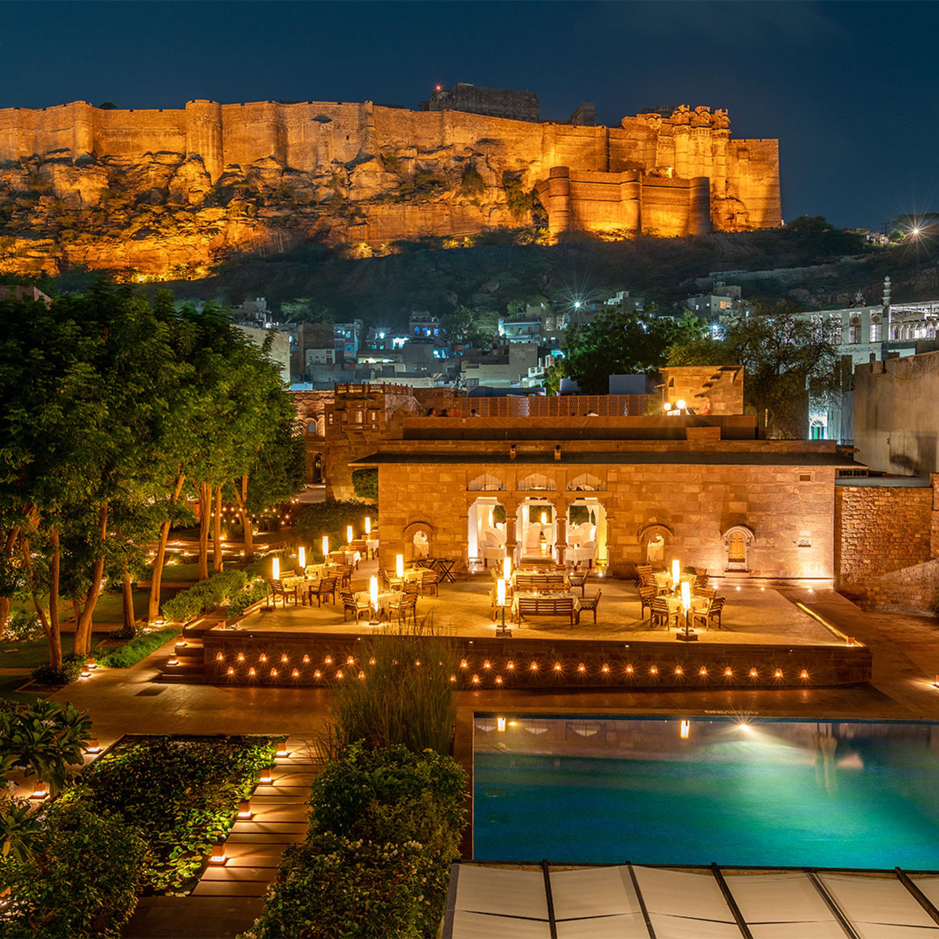 A terrace lit at night, with the fort lit on the hill behind