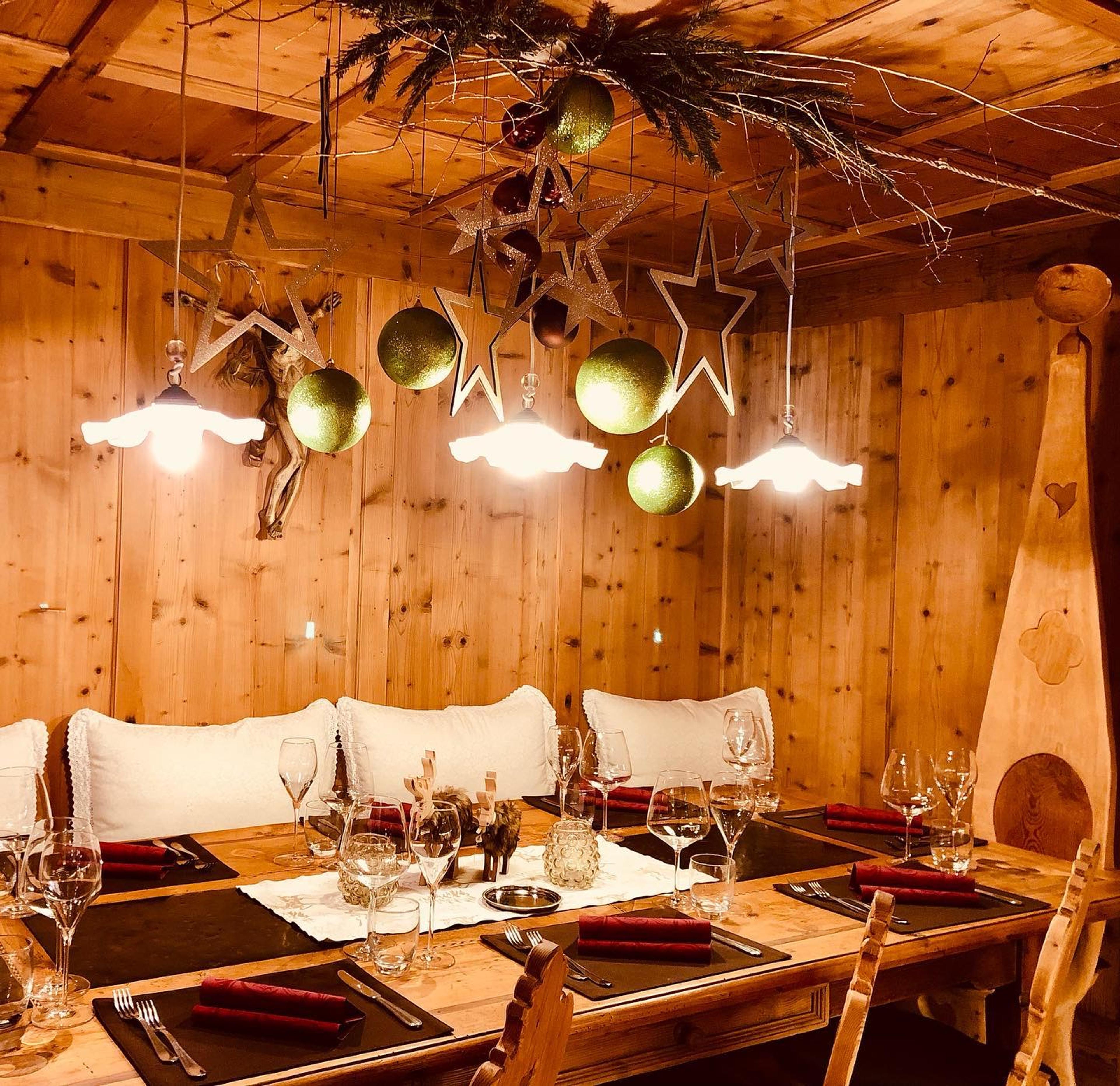 A pine-lined dining room with cushioned benches under hanging copper lamps