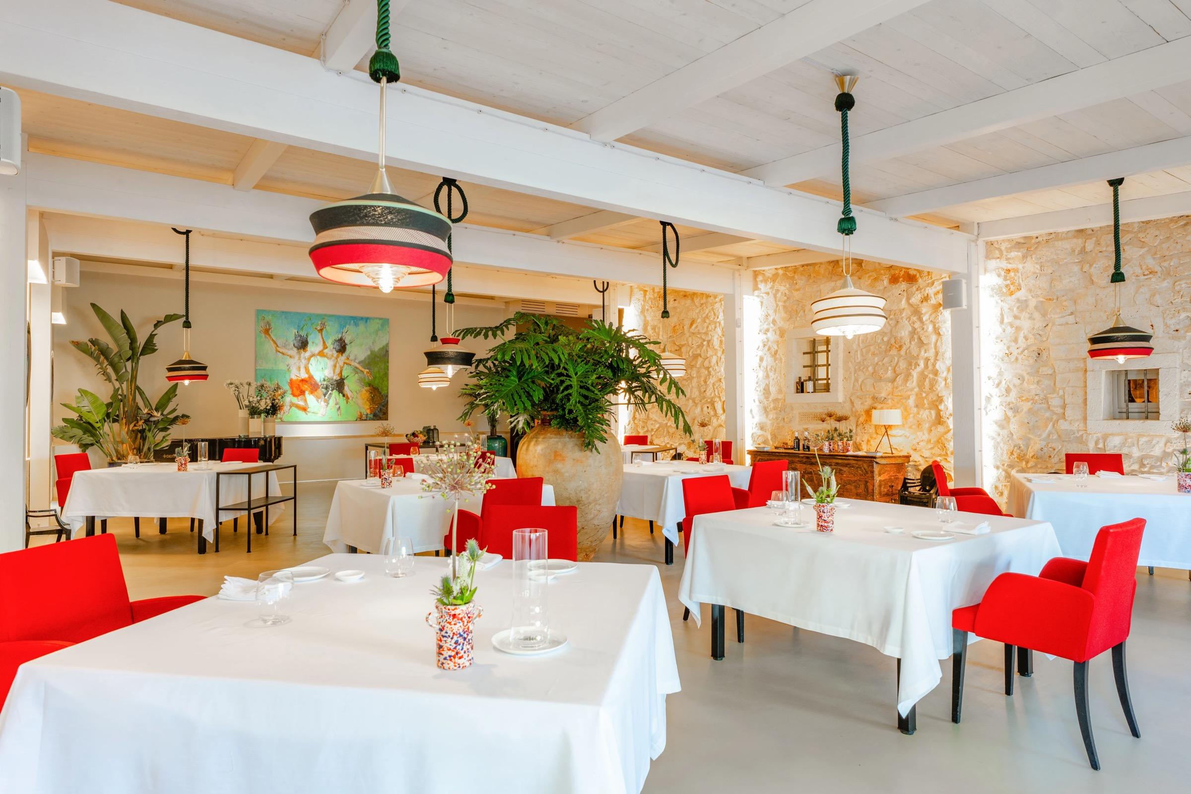 Pasha's bright dining room, white tablecloths and red chairs under a striped lamp