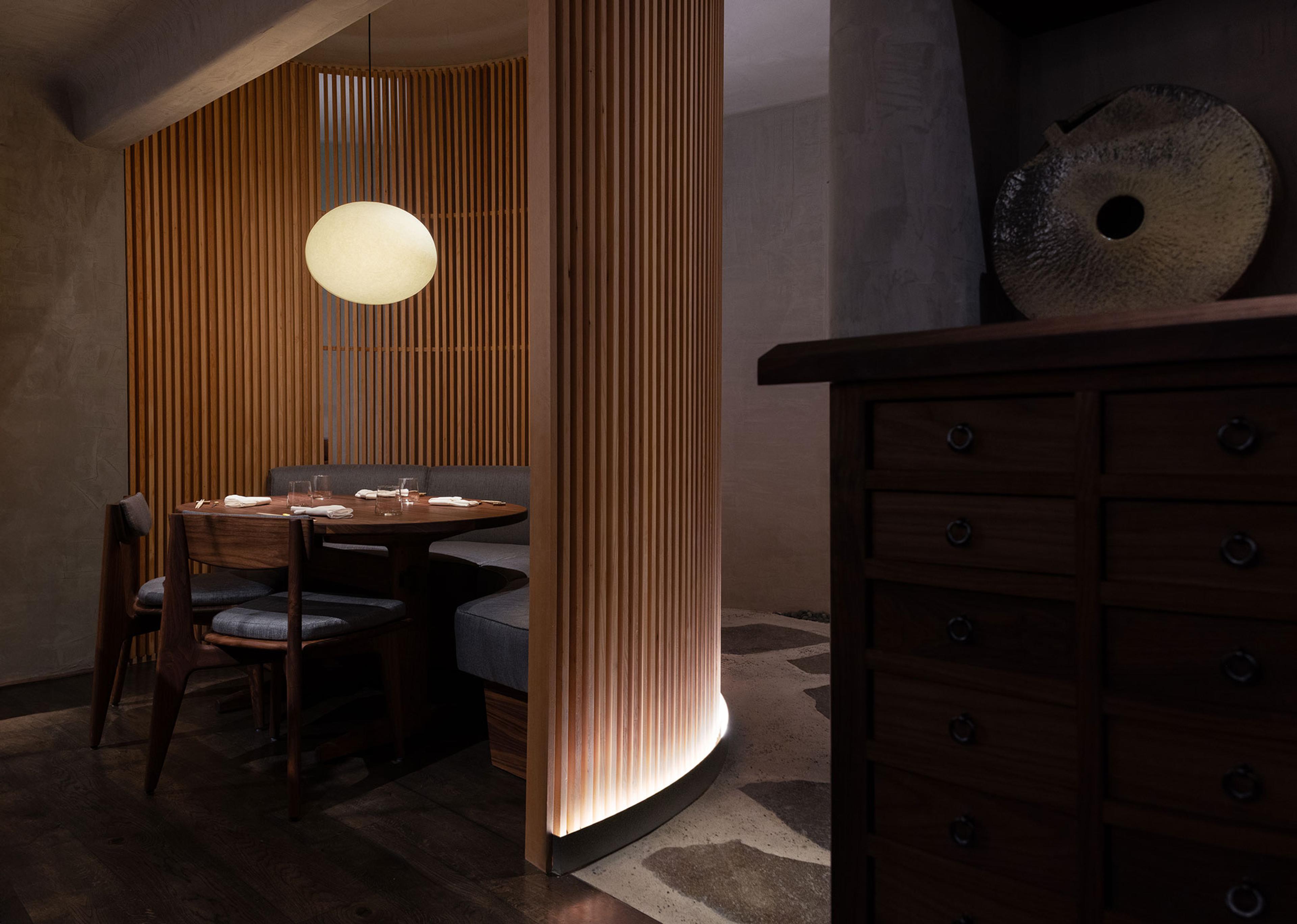 A private dining room at n/naka behind wooden slatted screens, lit by a single paper lamp
