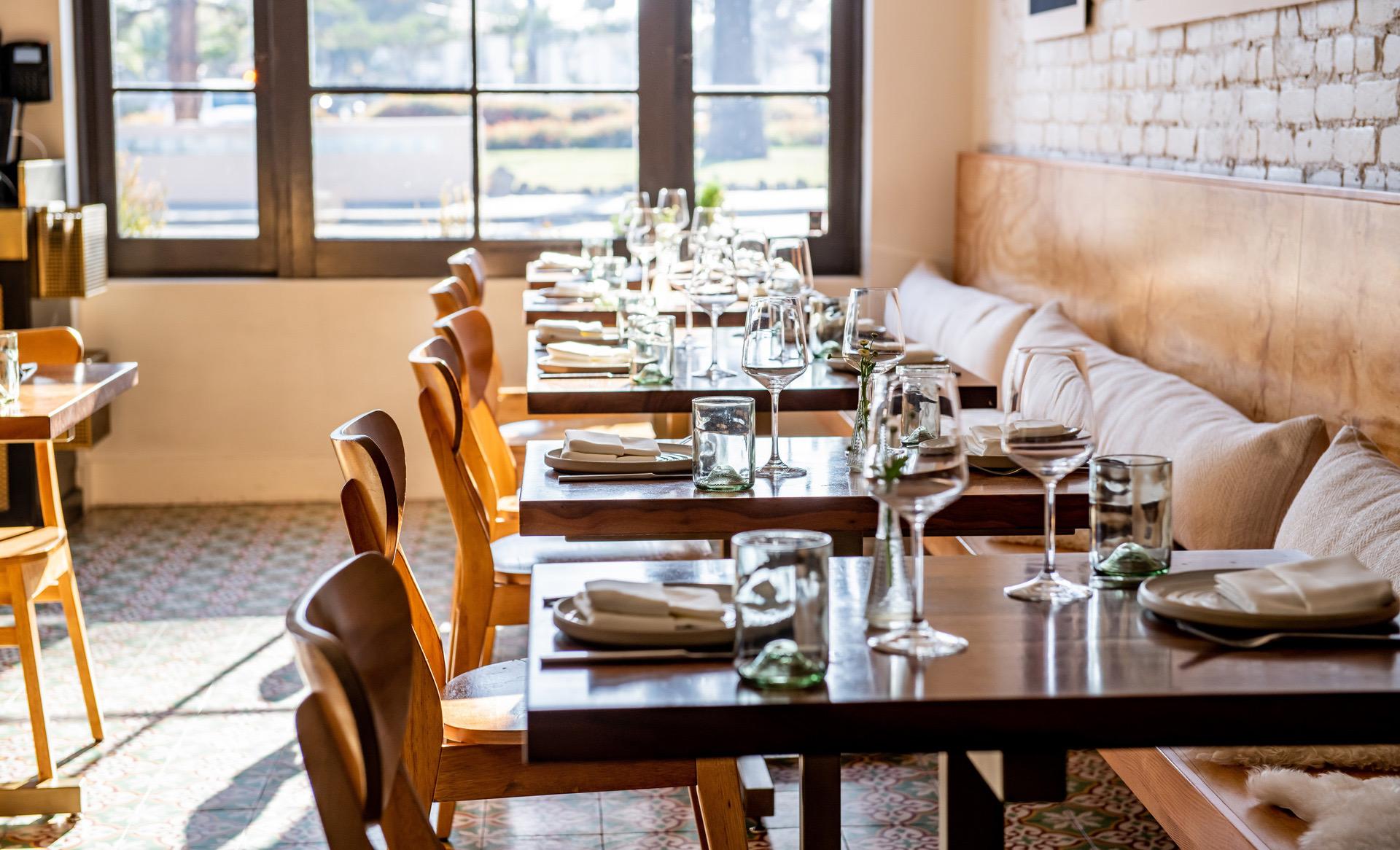 A long row of laid tables down Loquita's dining room beside tall windows