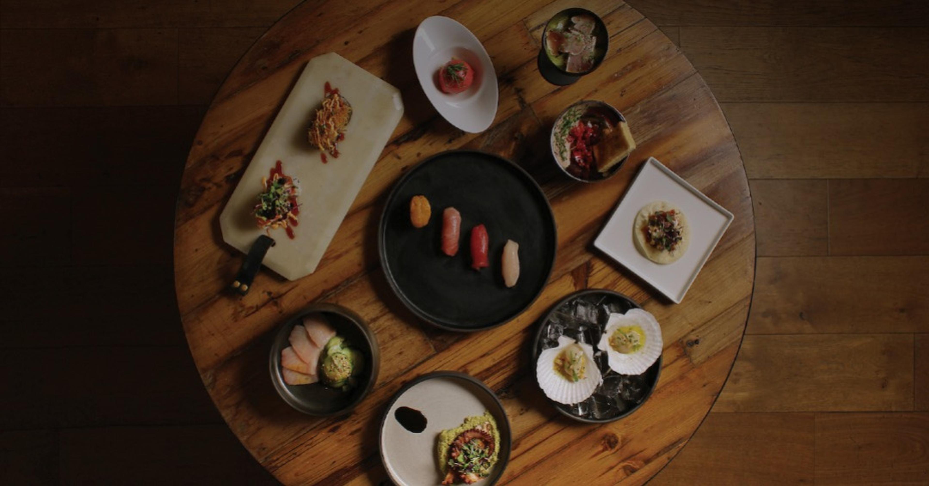 Sushi and small plates on a dark table, seen from above