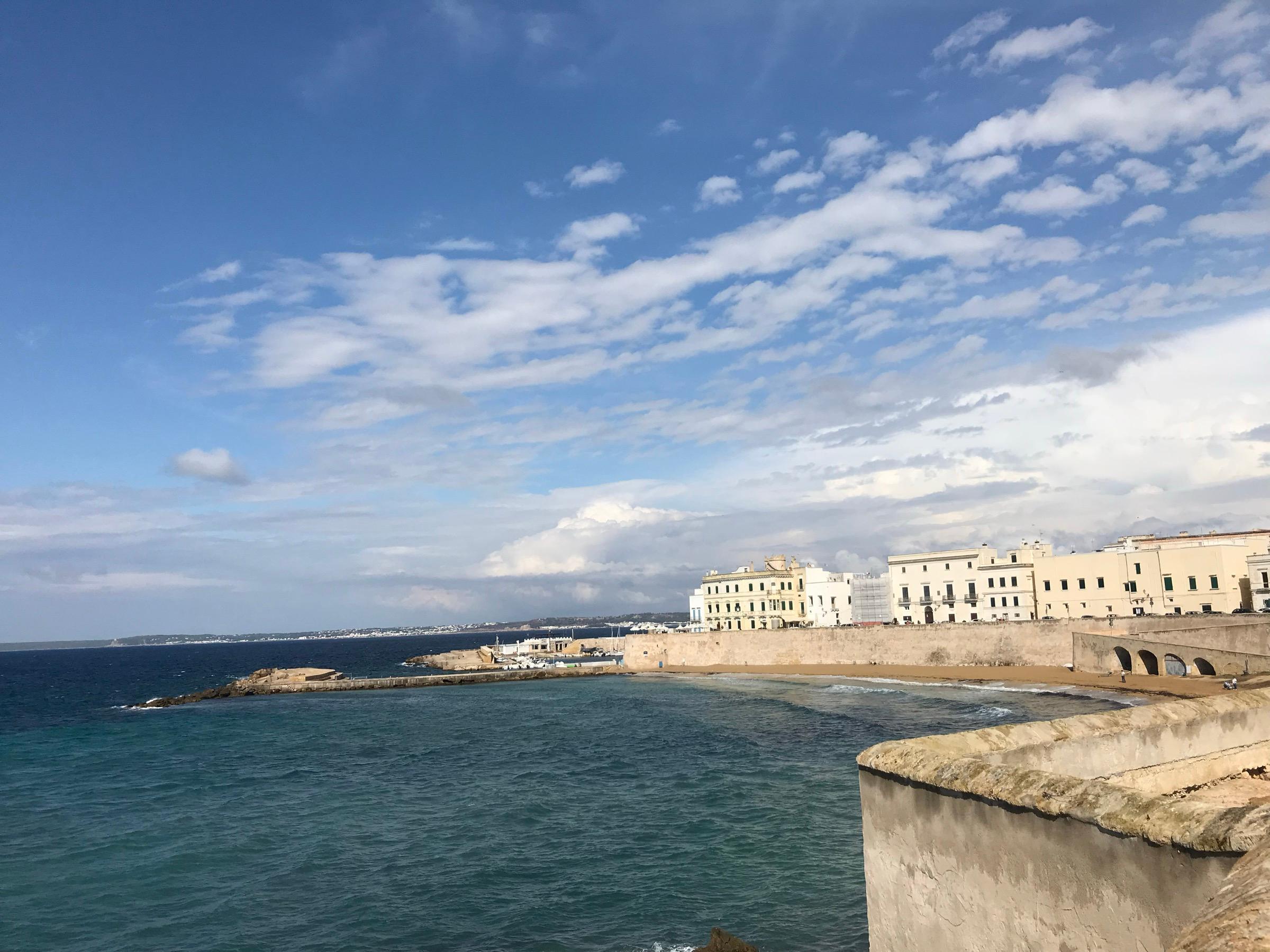 Gallipoli's old town on the Ionian, pale seafront houses along the walls and the sea beyond