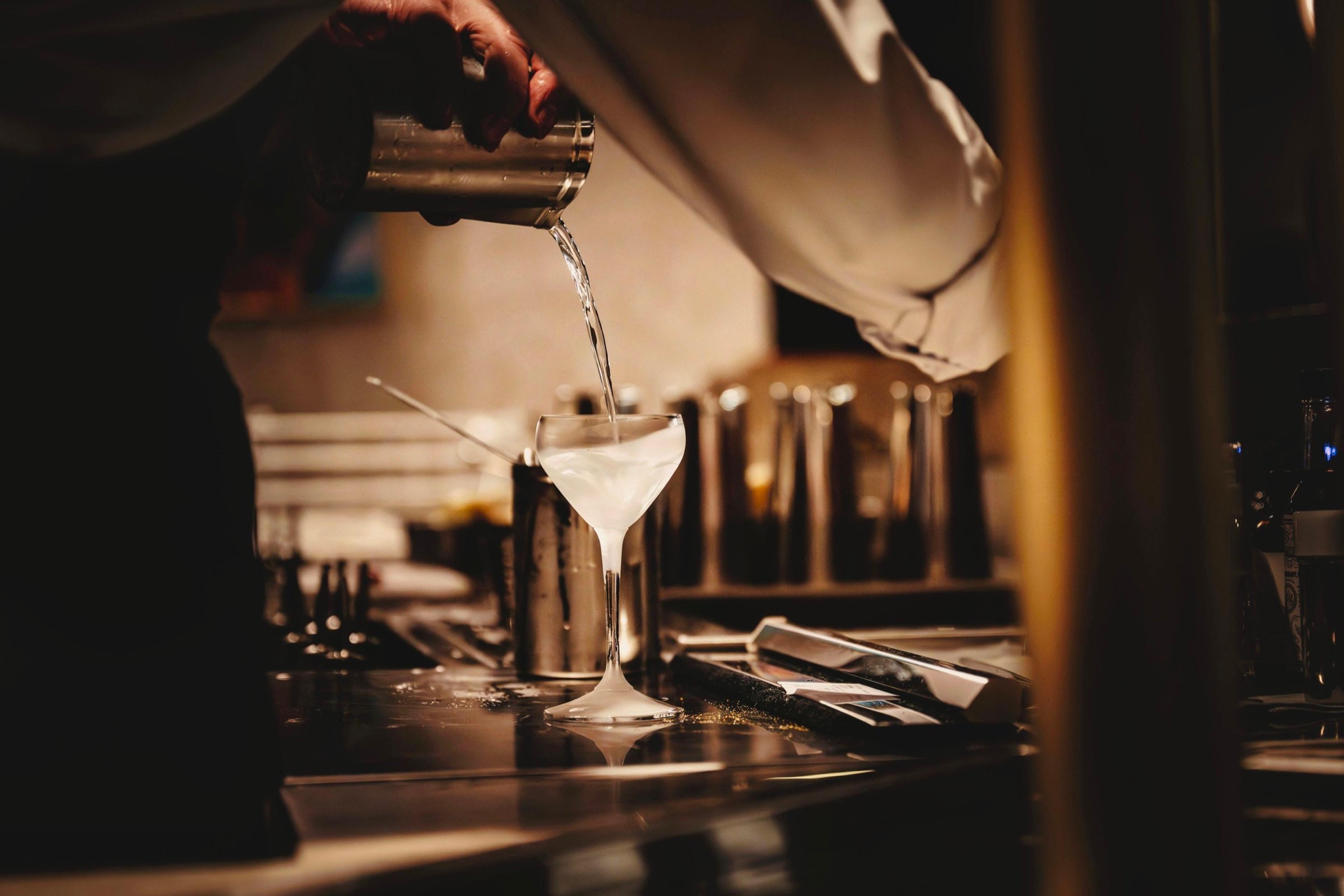 A cocktail strained into a coupe at a dimly lit bar