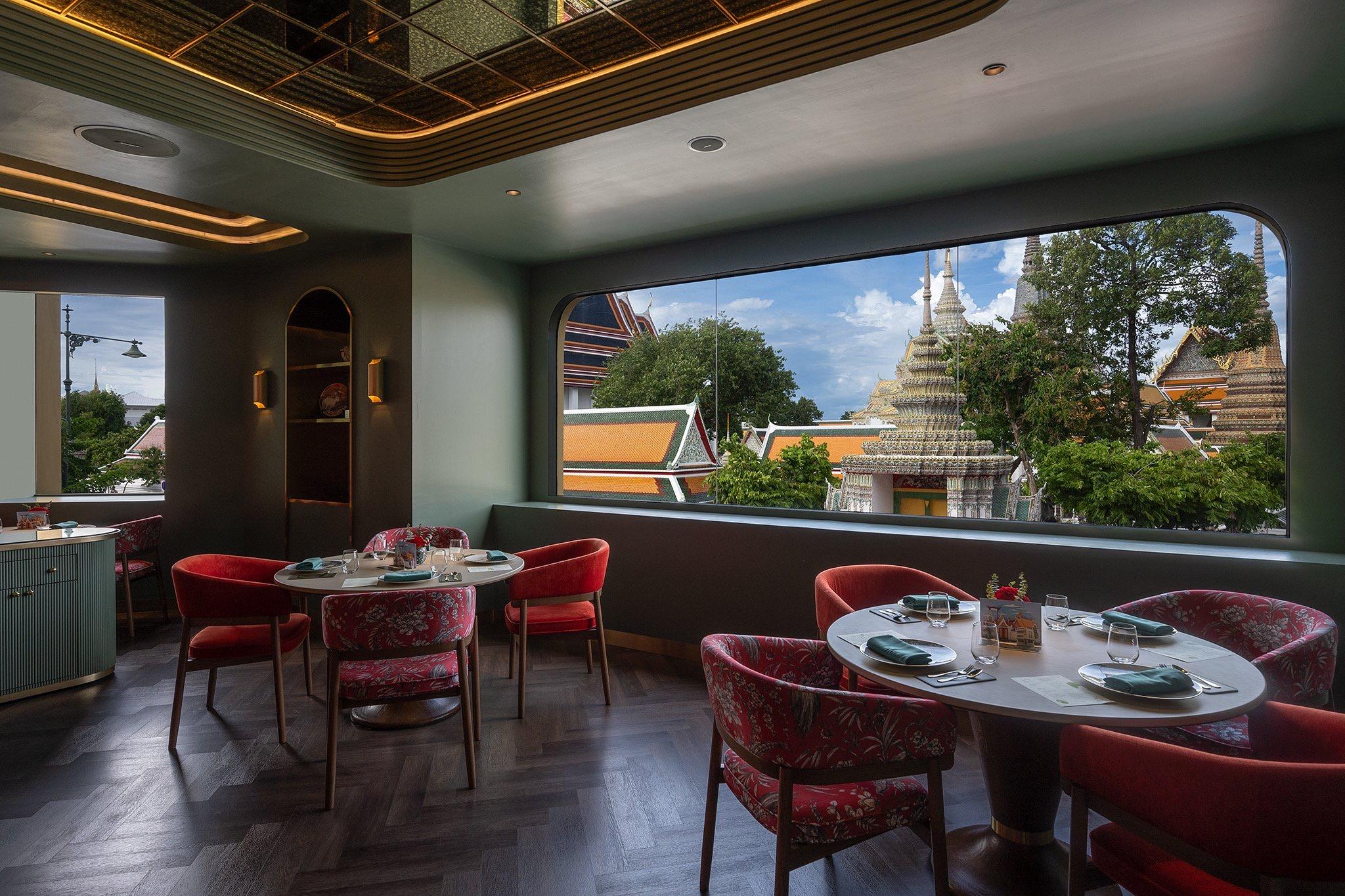 A dining room with white-clothed tables and wide windows onto a temple roof