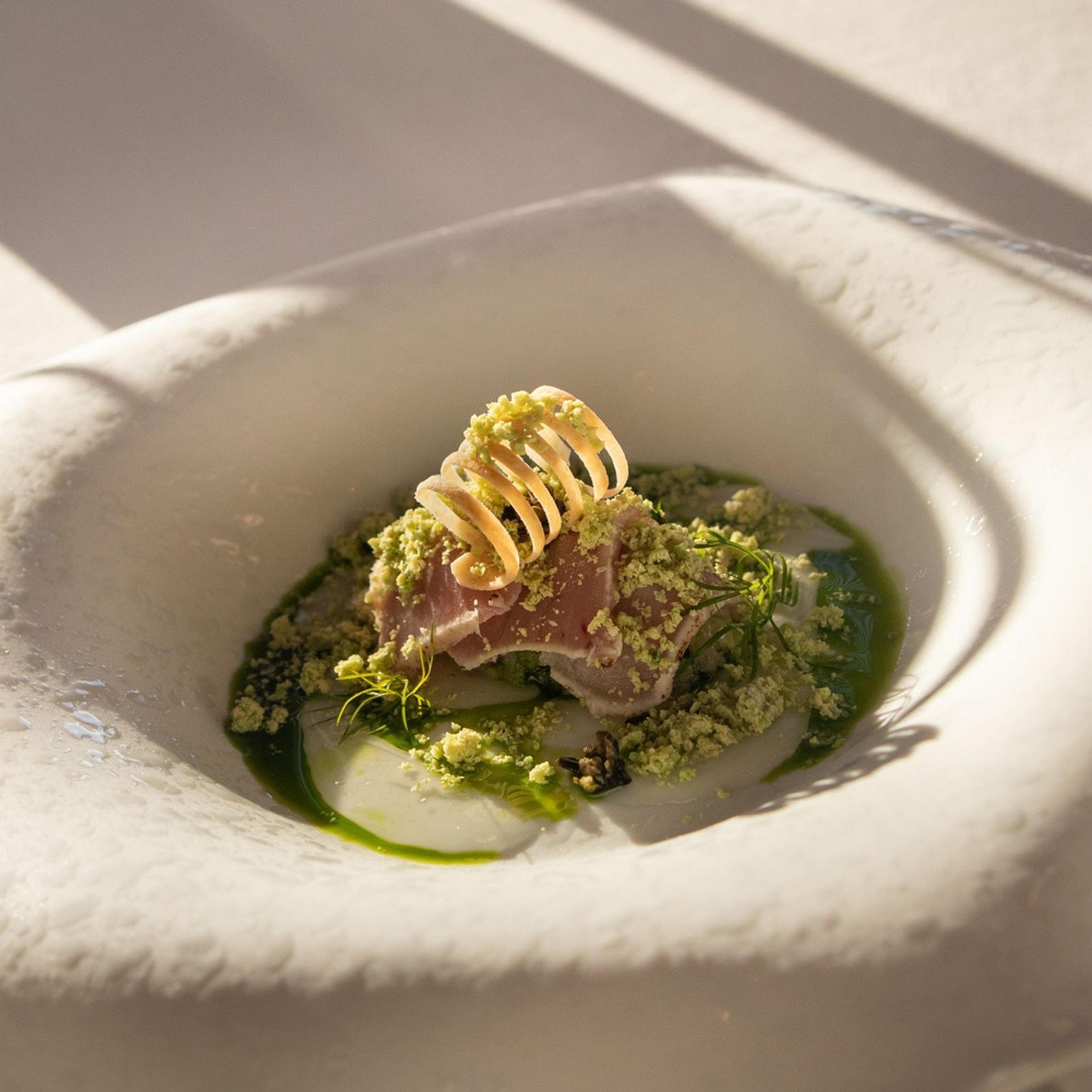 A course at M.B in a deep white bowl, with a green sauce