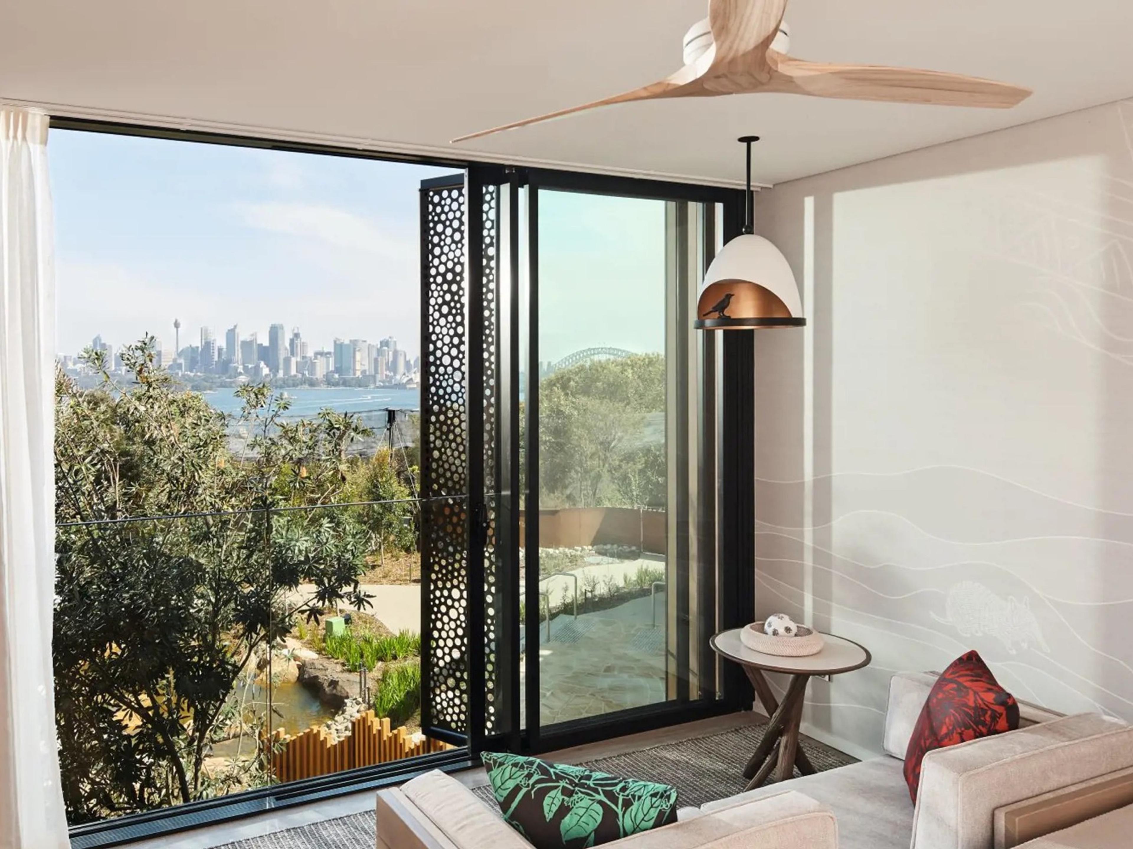 The city skyline and the Harbour Bridge across the water, seen through open doors from a room above the harbour's bushland