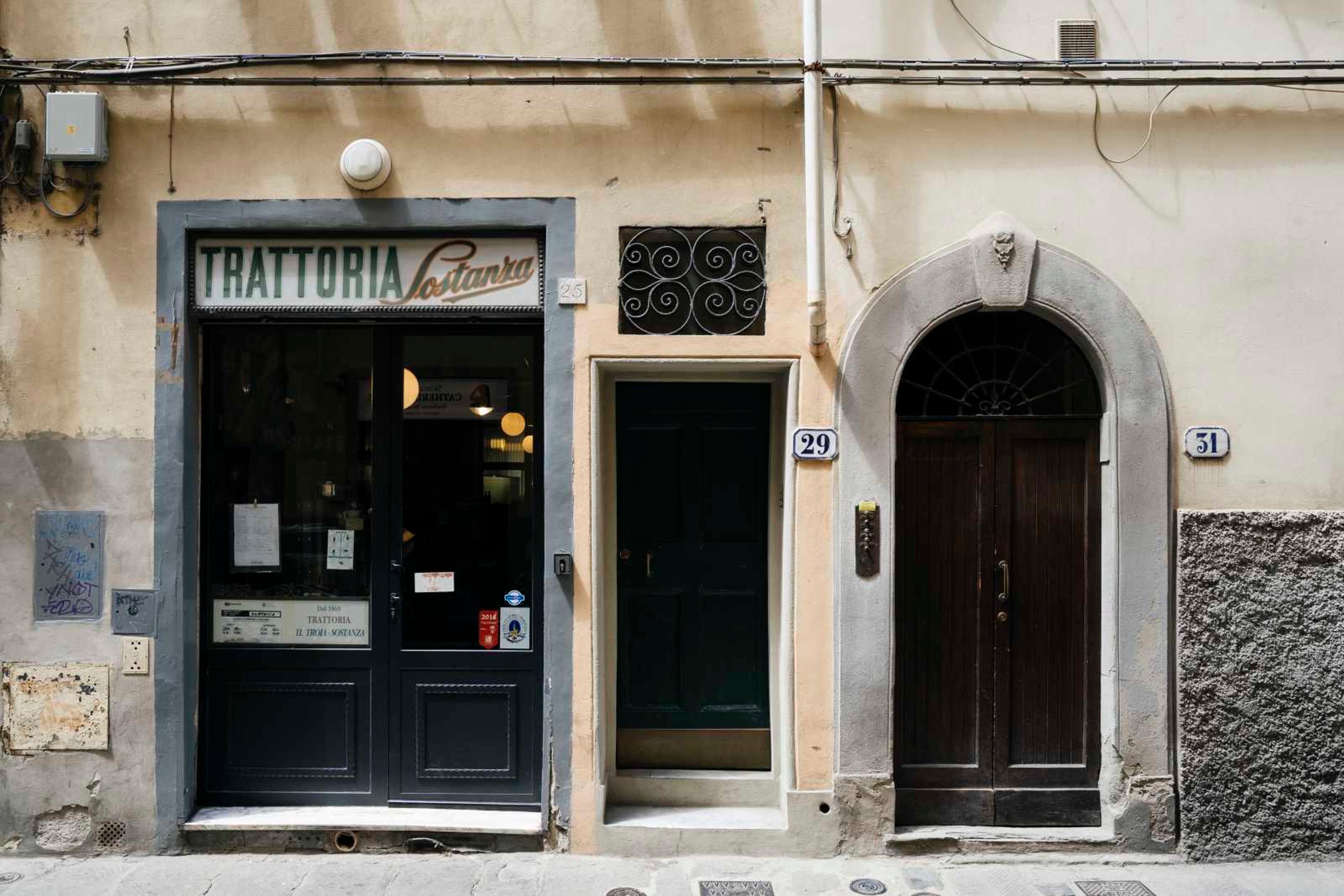 The front of Trattoria Sostanza on Via del Porcellana, its name over a dark glass door