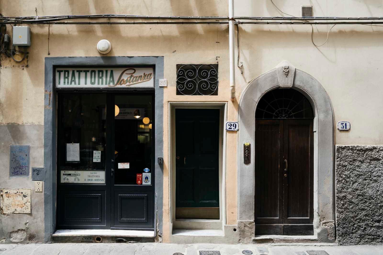 The front of Trattoria Sostanza on Via del Porcellana, its name over a dark glass door