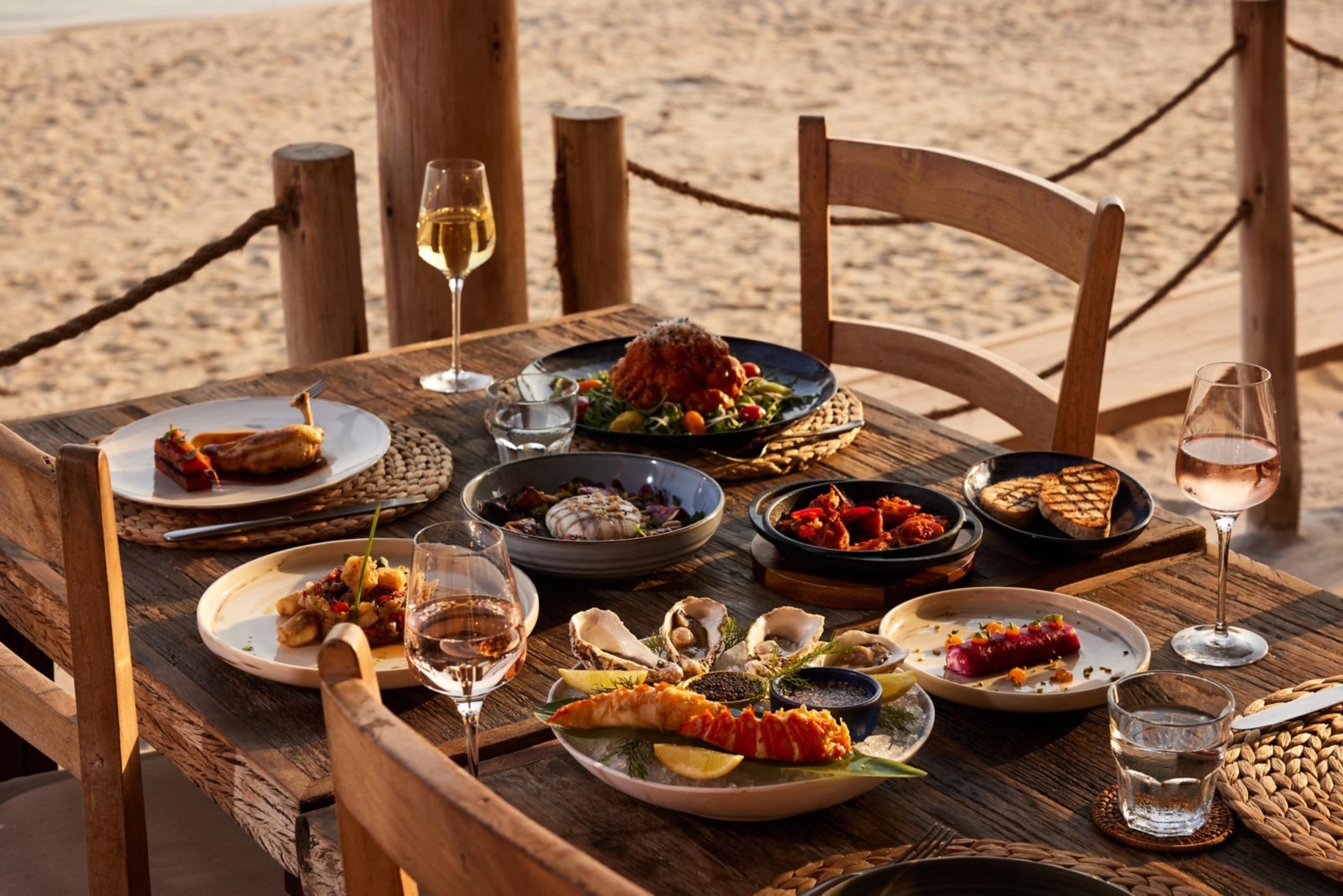 A table of dishes and wine set out on the sand at Laguna Beach Taverna