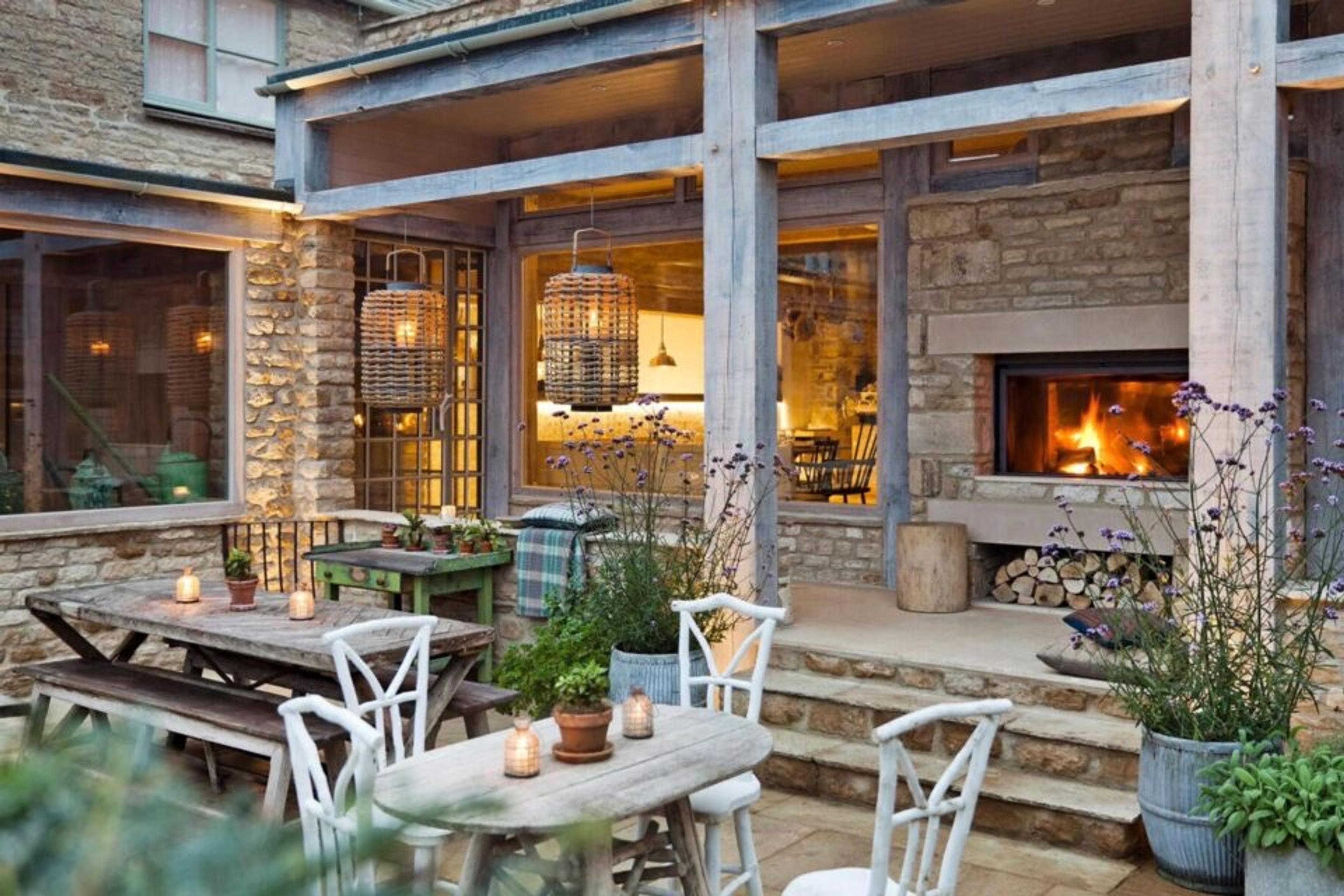 A stone-walled terrace with tables set outside a glass-fronted dining room