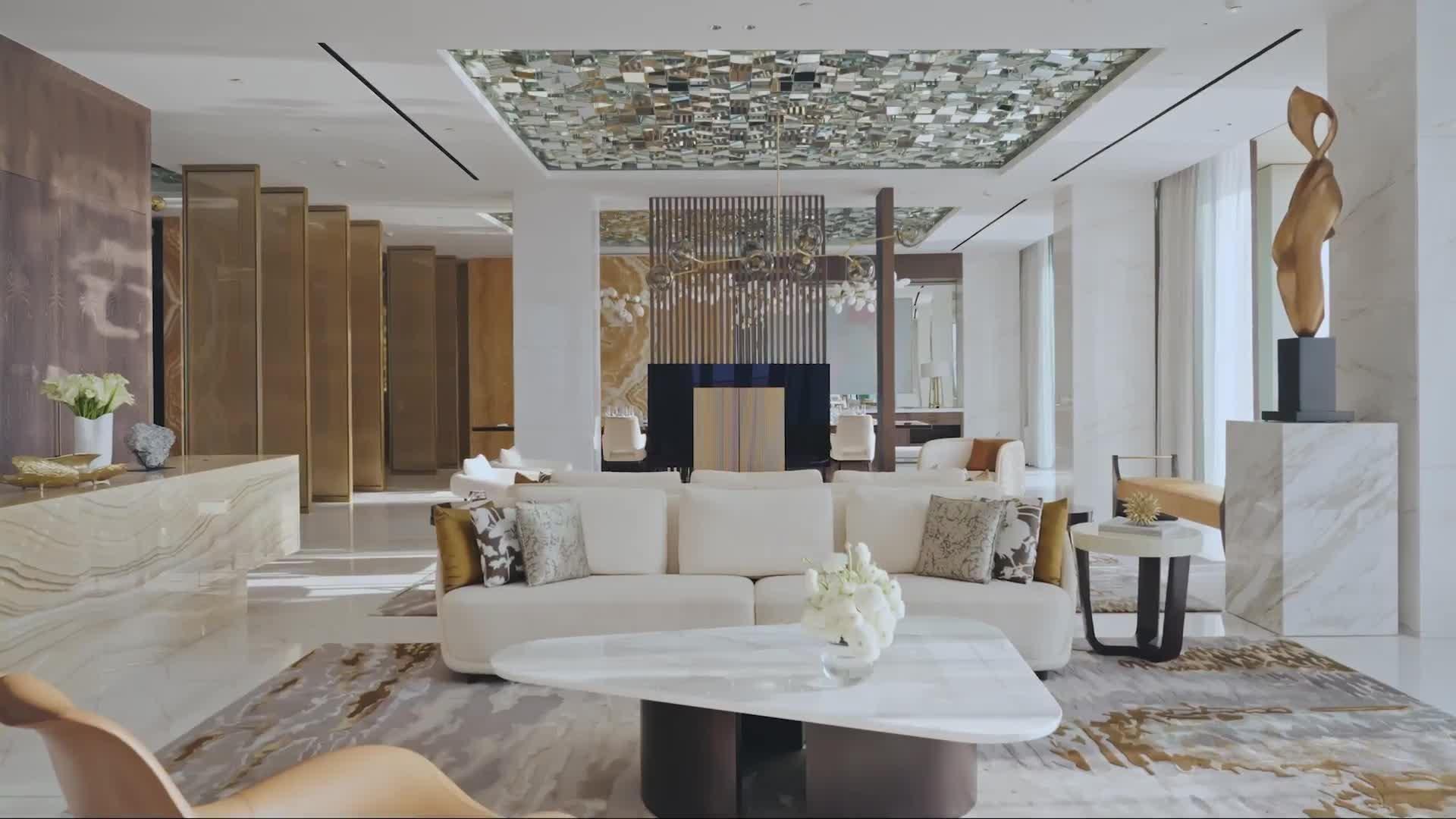 A hotel bedroom with a white bed, a wood accent wall, and a sitting area in front of a floor-to-ceiling window over the water.