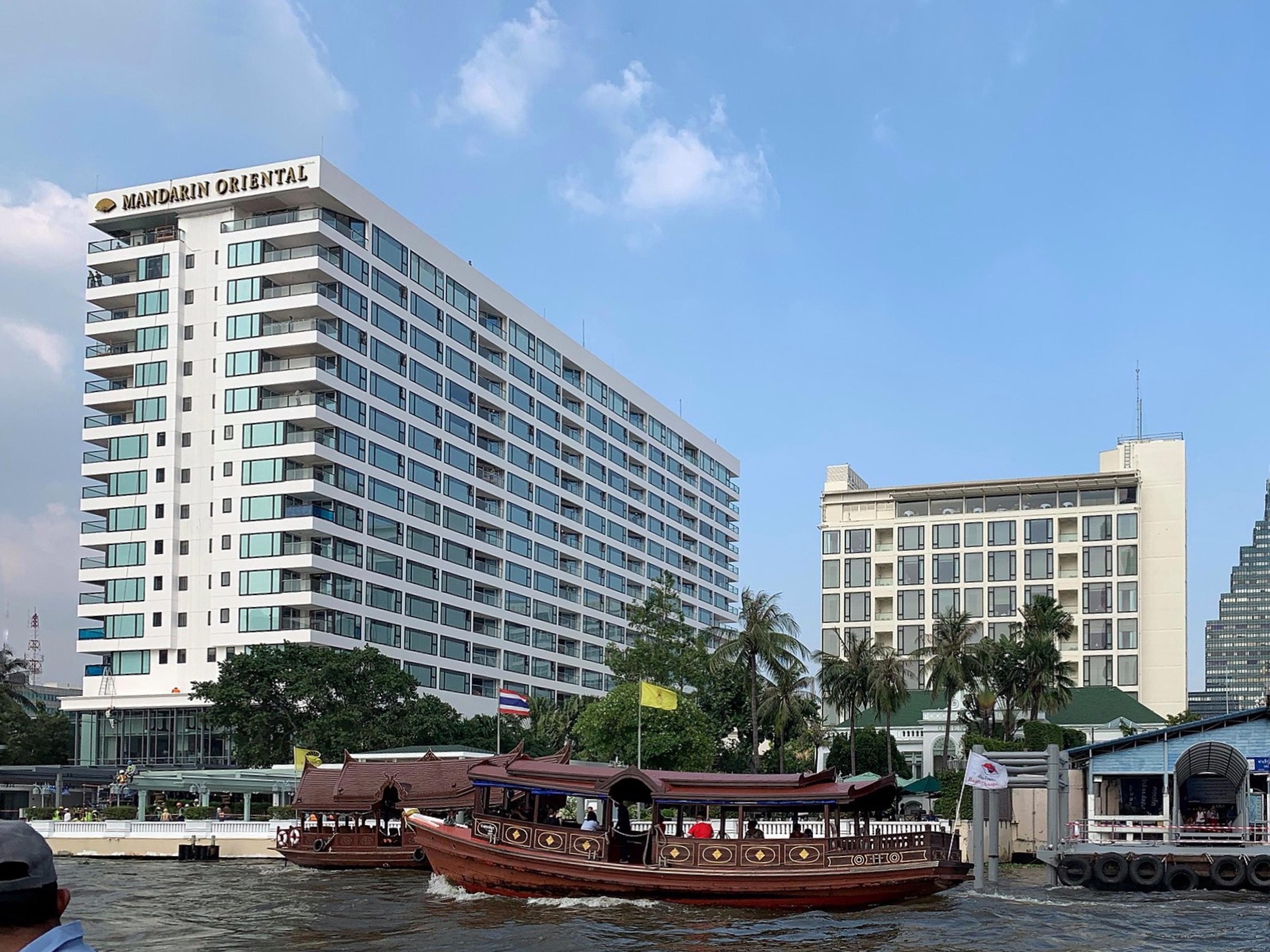 The hotel's white river wing on the Chao Phraya, with a boat at the landing