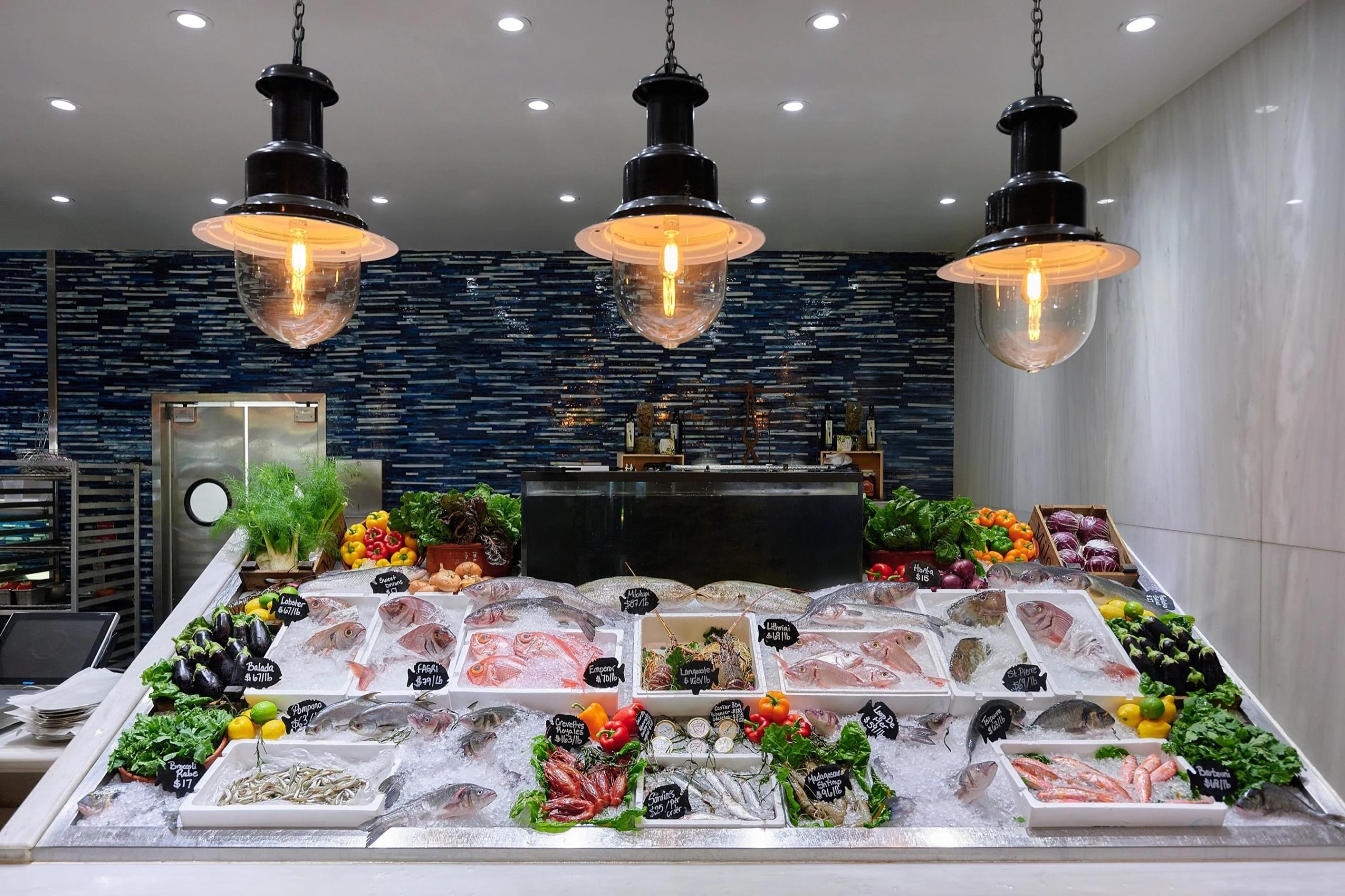The day's fish laid out on ice under hanging lamps, against a tiled wall
