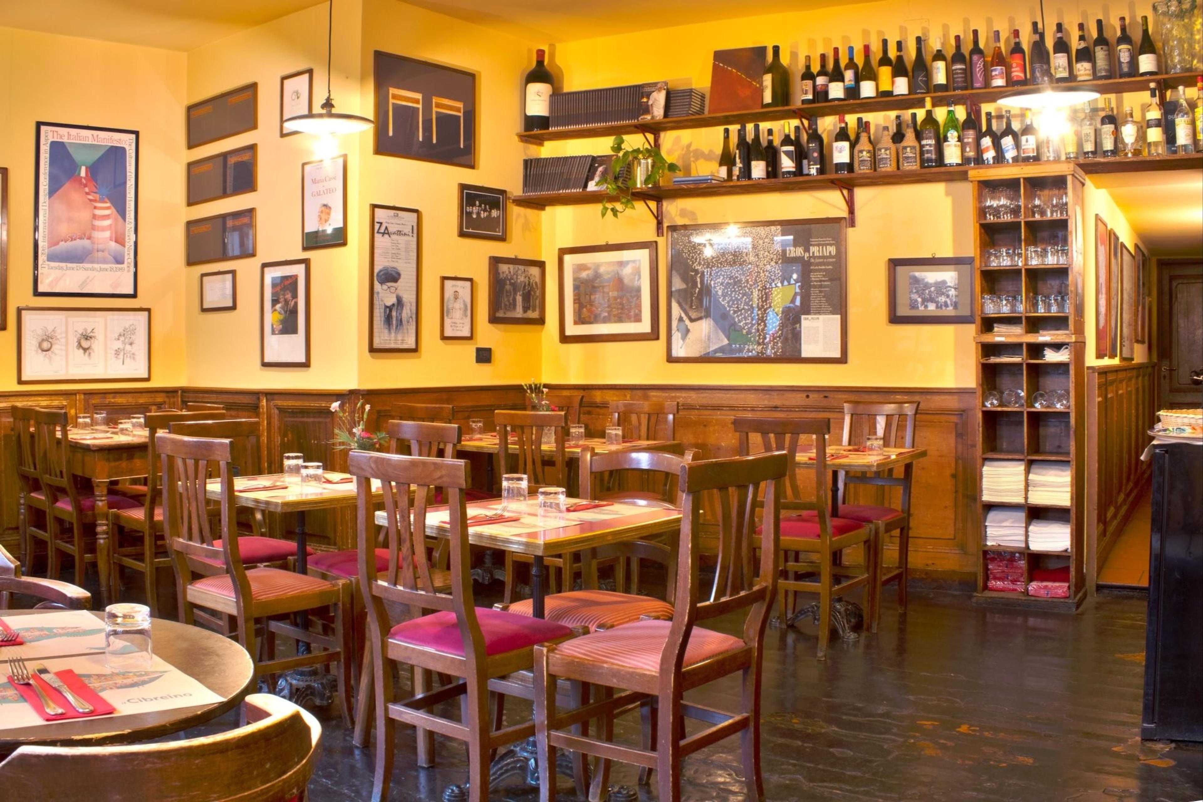 Inside Il Cibrèino, small tables against walls hung with pictures