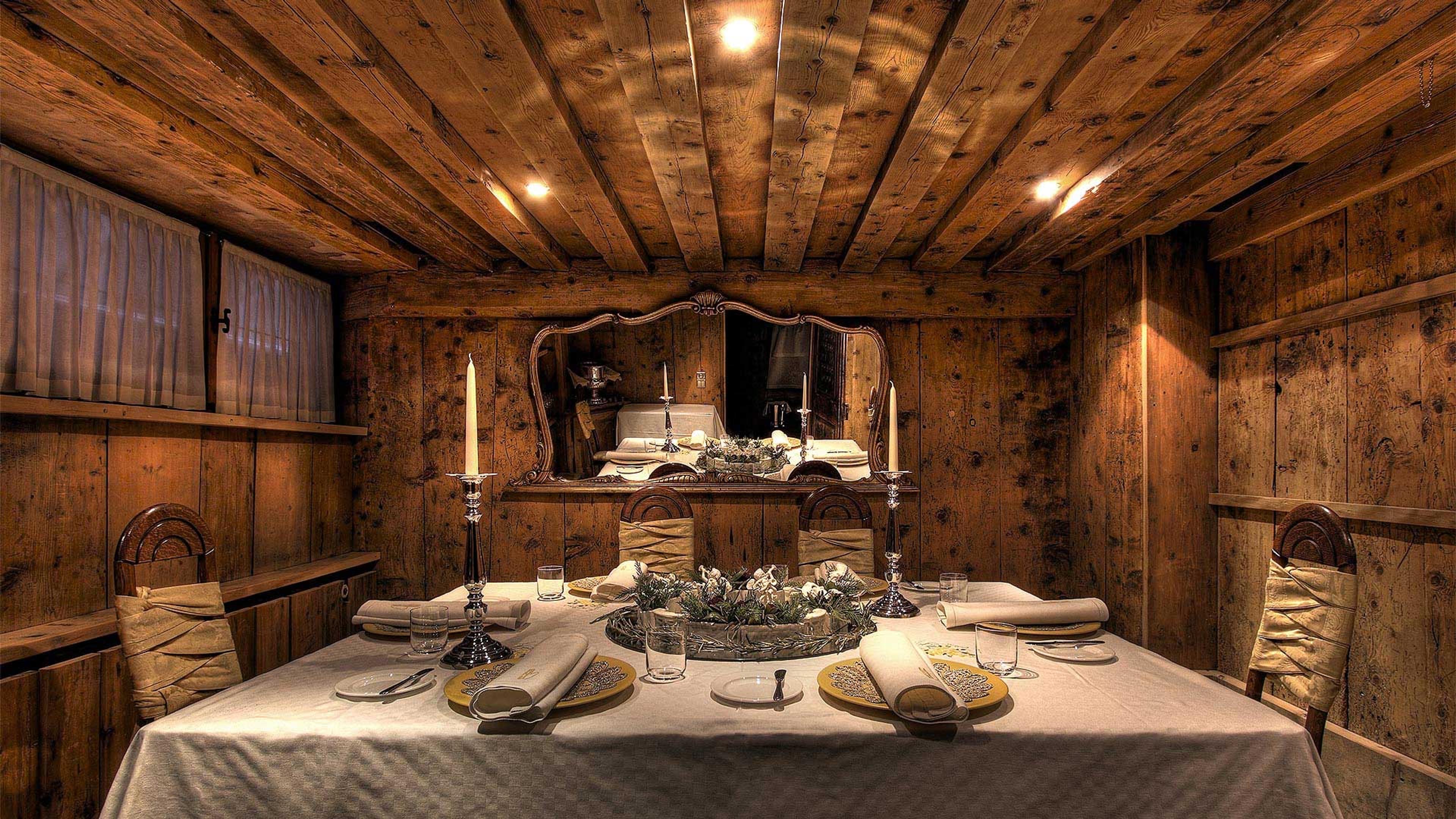 A wood-panelled stube with a carved ceiling, its table laid under candlelight