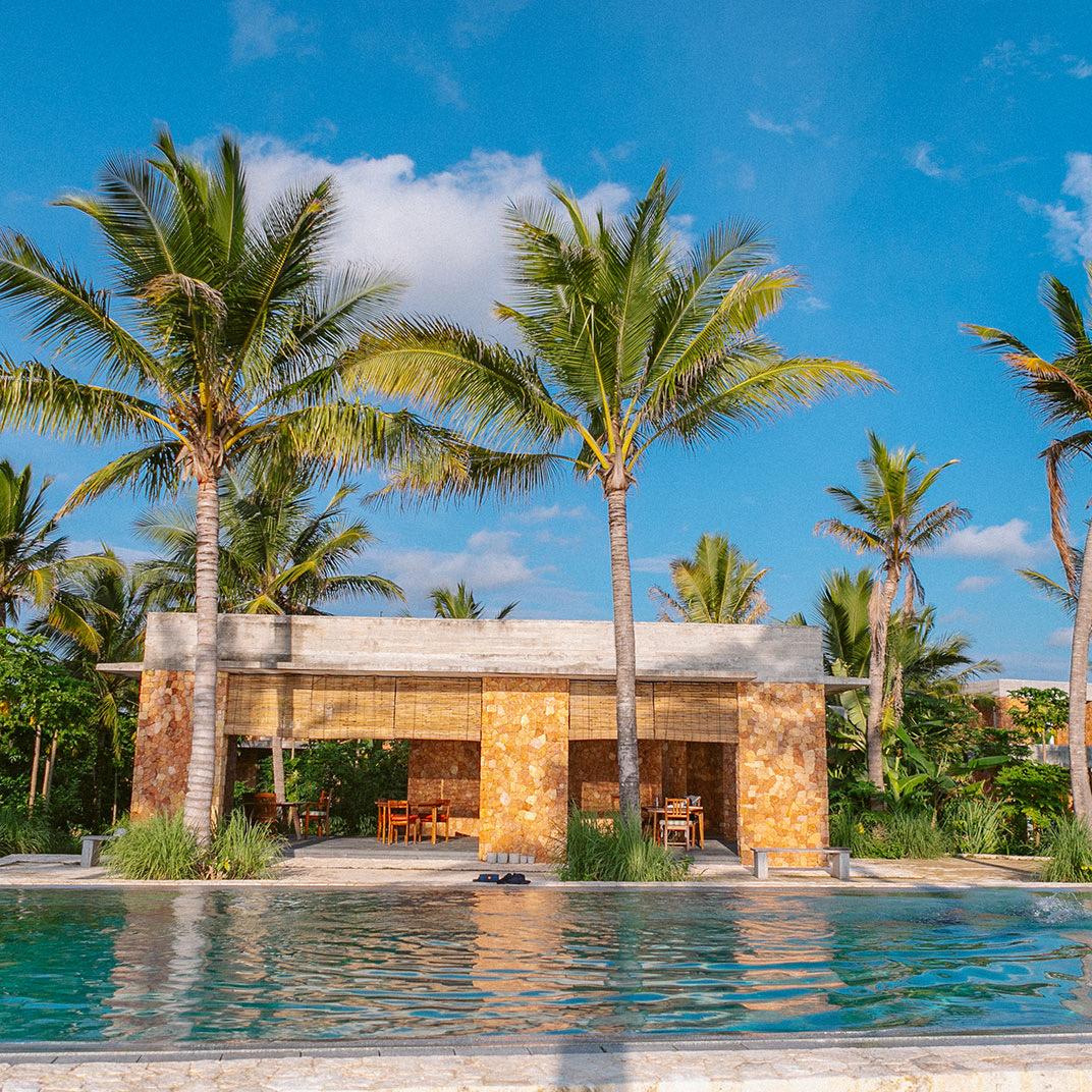 A coral-stone building among palms beside the pool