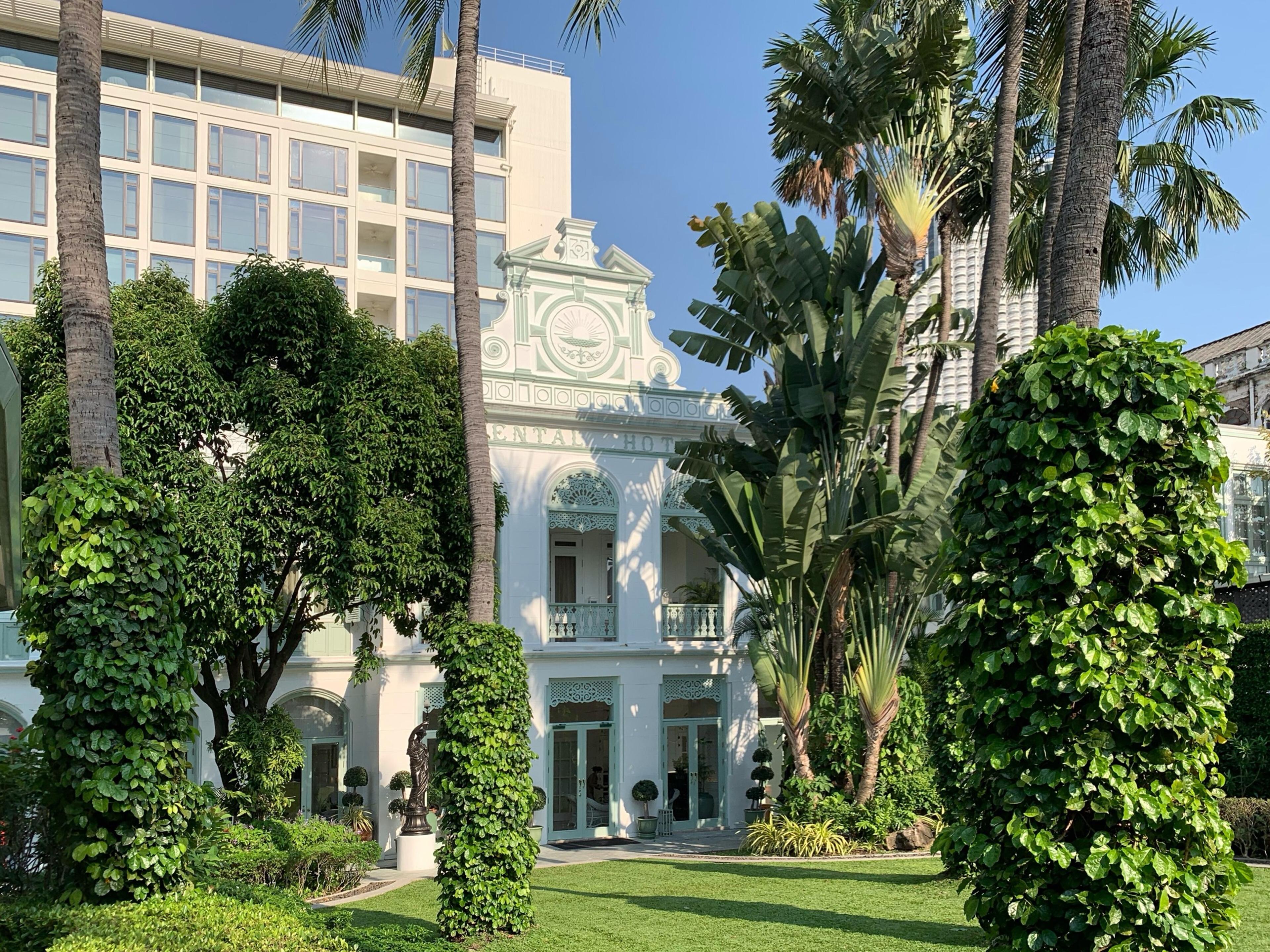 The white colonial Authors' Wing behind palms and a clipped hedge