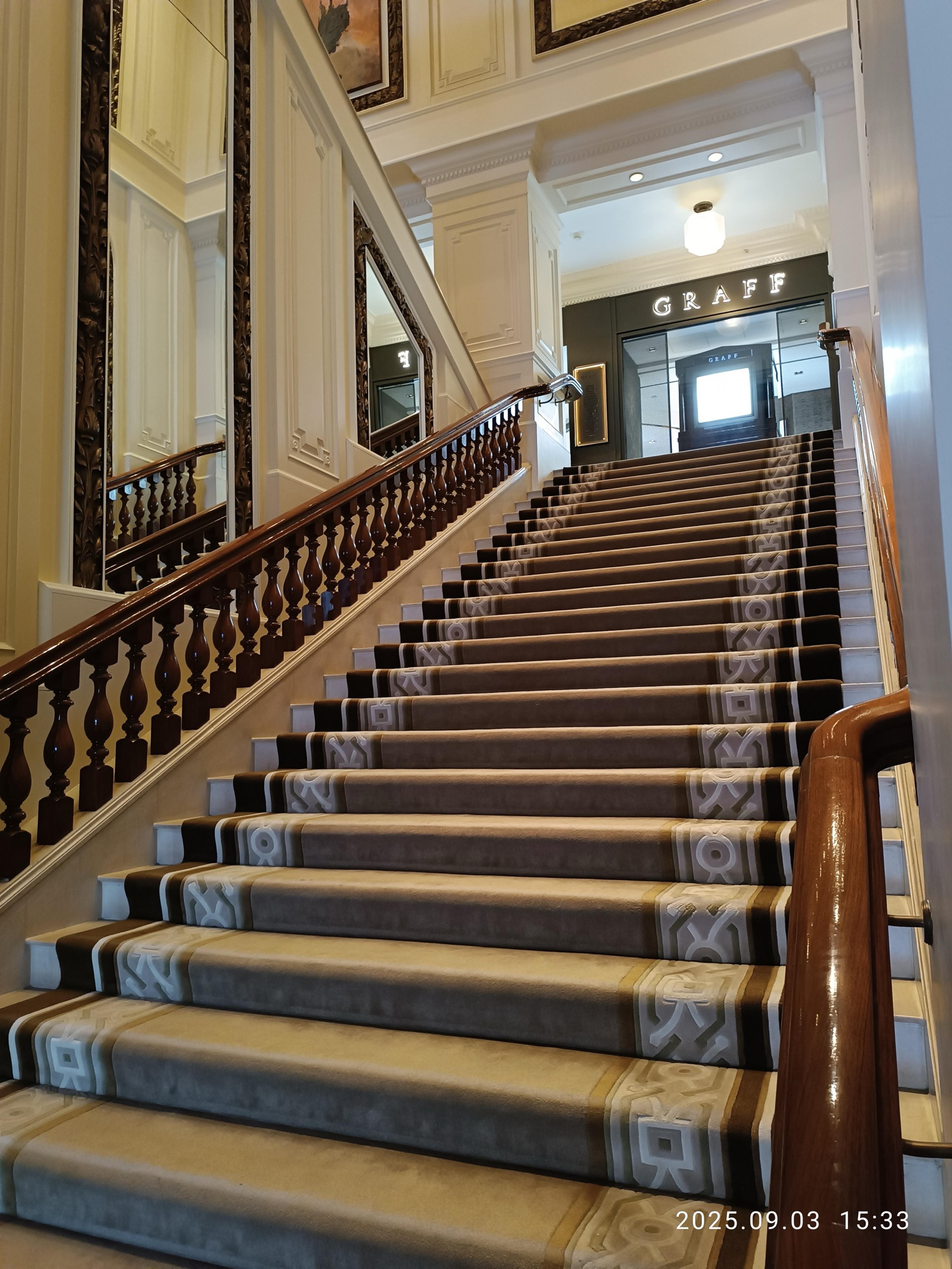 A grand carpeted staircase with a dark wooden balustrade