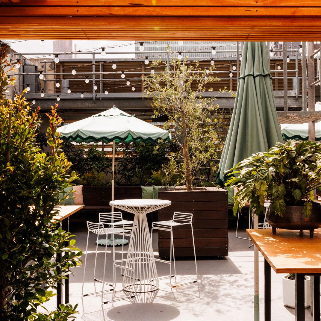 A leafy terrace with tables under umbrellas