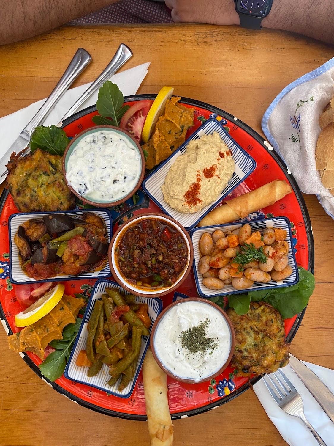 A meze platter at Small House: hummus, cacık, haydari, beans, aubergine and courgette fritters on a painted plate